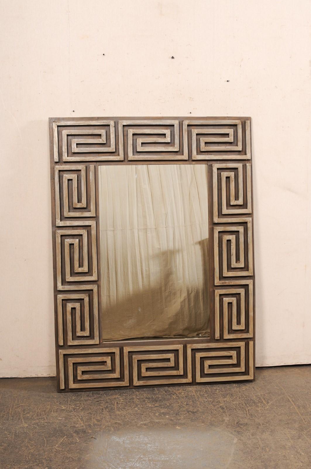 Uno specchio realizzato artigianalmente con motivo a chiave greca intagliato e circondato da un vecchio legno di recupero. Questo specchio personalizzato è caratterizzato da un disegno in legno a rilievo con un motivo a chiave greca ripetuto che