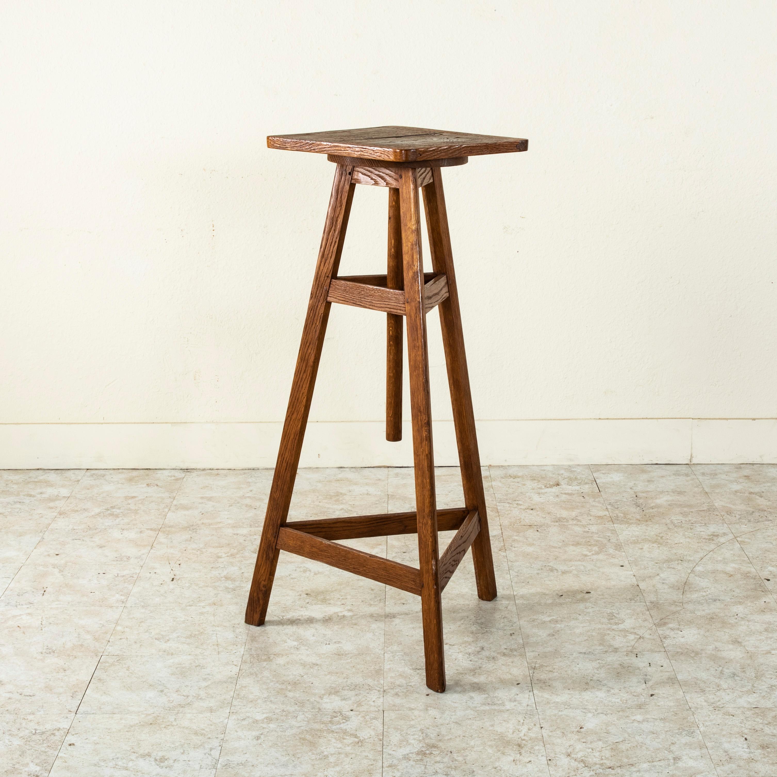 This artisan-made oak sculptor's table from France stands ready to accommodate any oeuvre d'art. Hand pegged with mortise and tenon construction, it is supported by three legs and has a 15.5 inch square top that rotates, allowing the artist to turn