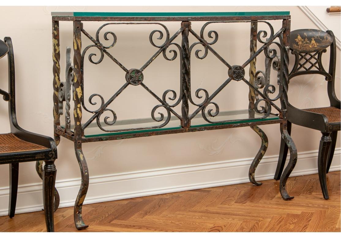 Custom wrought iron console table, with lower glass tier, having two X-form panels conjoined with C-scrolls and a round floral medallion. The custom 3/4