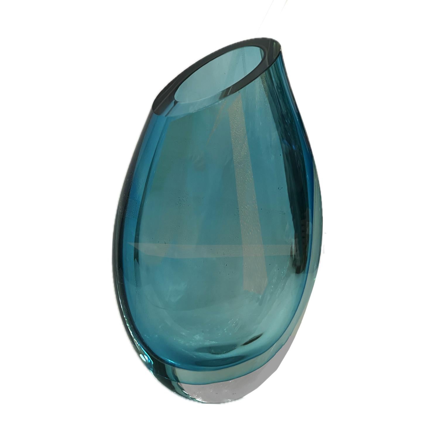 Jarrón de cristal de Murano soplado a mano y meticulosamente elaborado  en ricos tonos cambiantes de  turquesa con bandas de avventurina dorada que brillan y se desvanecen con los cambios de  Luz.  La elegante almendra  recipiente con forma  de