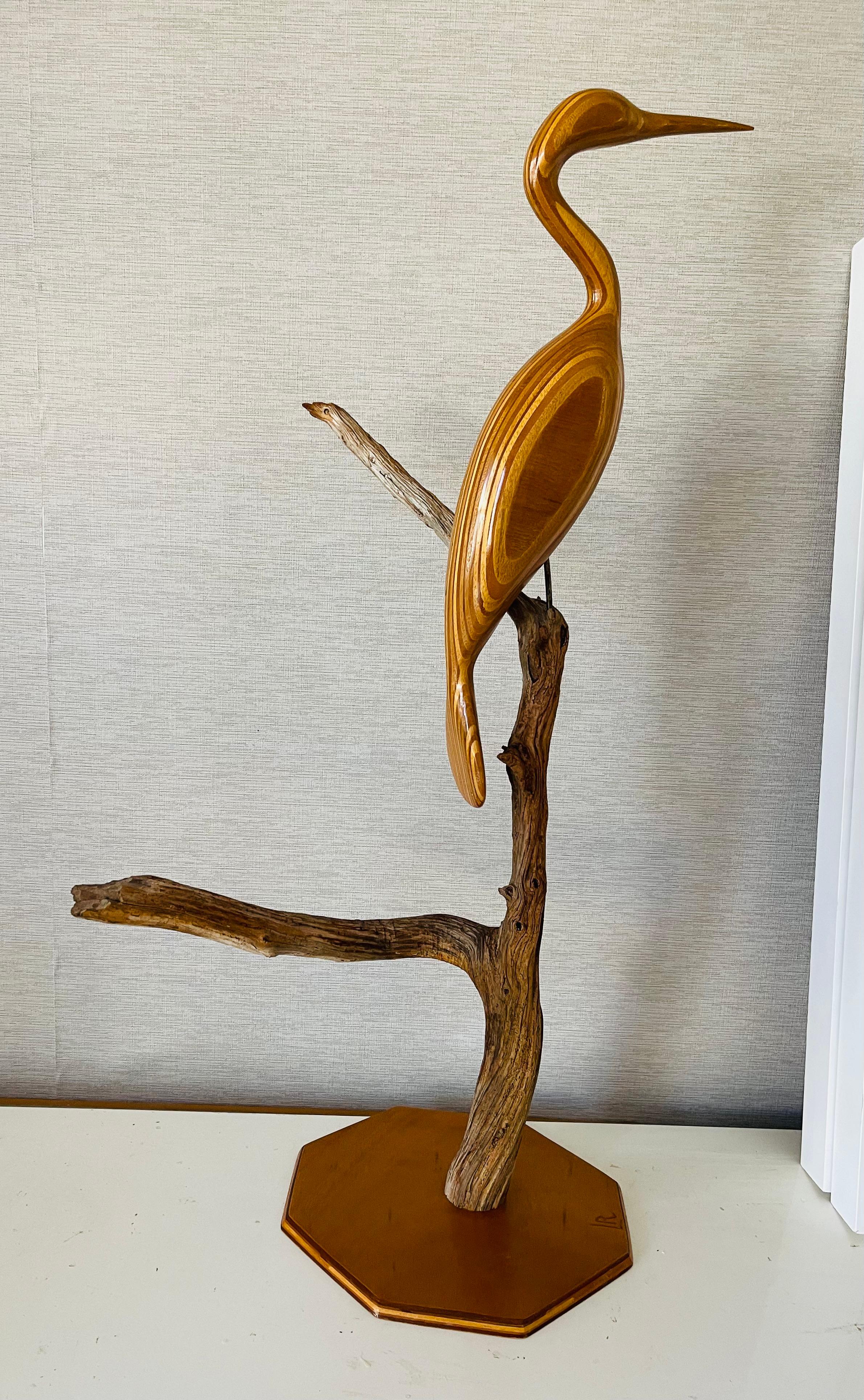 Escultura artesanal vintage tallada a mano en madera de olivo con forma de garza sobre un brunch de madera a la deriva. Con iniciales en la base LR. 