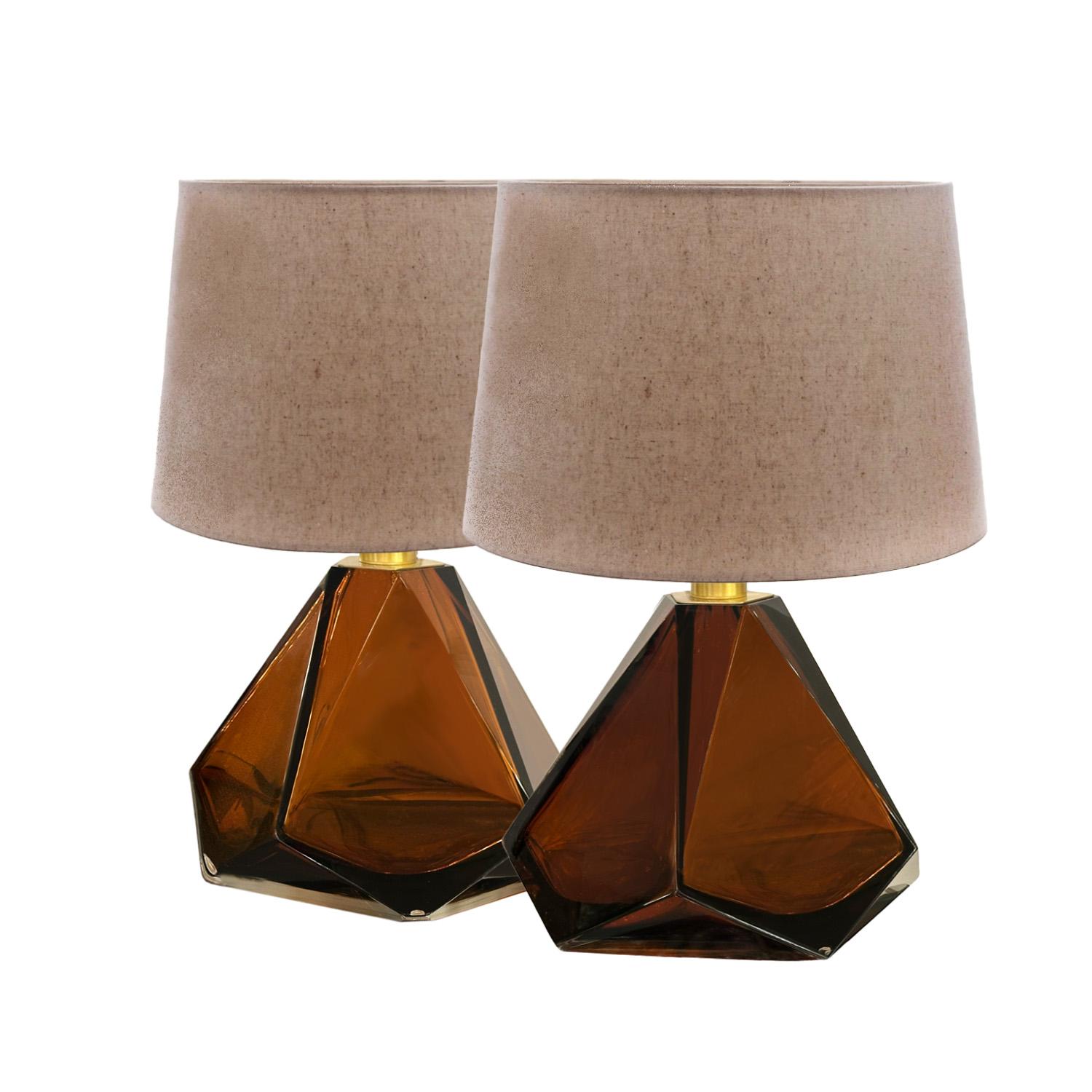 Grand size pair of faceted table lamps in Amber color Murano glass with brushed brass hardware.  These make a dramatic pair of bedside lamps or a chic and sculptural stand alone table lamp. Alternate colors are available. Please inquire with