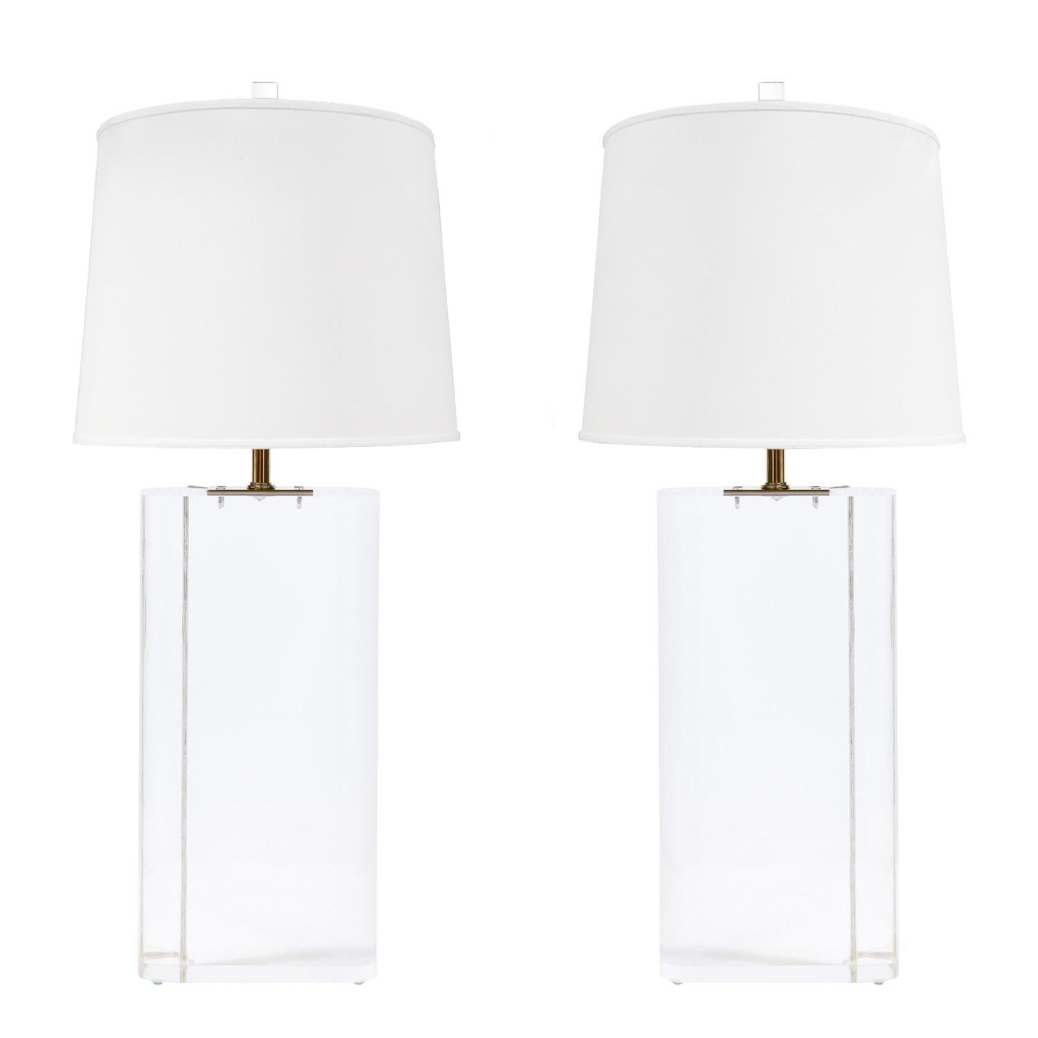 Pair of beautifully made large table lamps, solid clear lucite blocks with radius corners and mounted brass hardware, American 1970's.  Cords are embedded in the lucite blocks. Each lamp with a double socket cluster and adjustable riser to adjust
