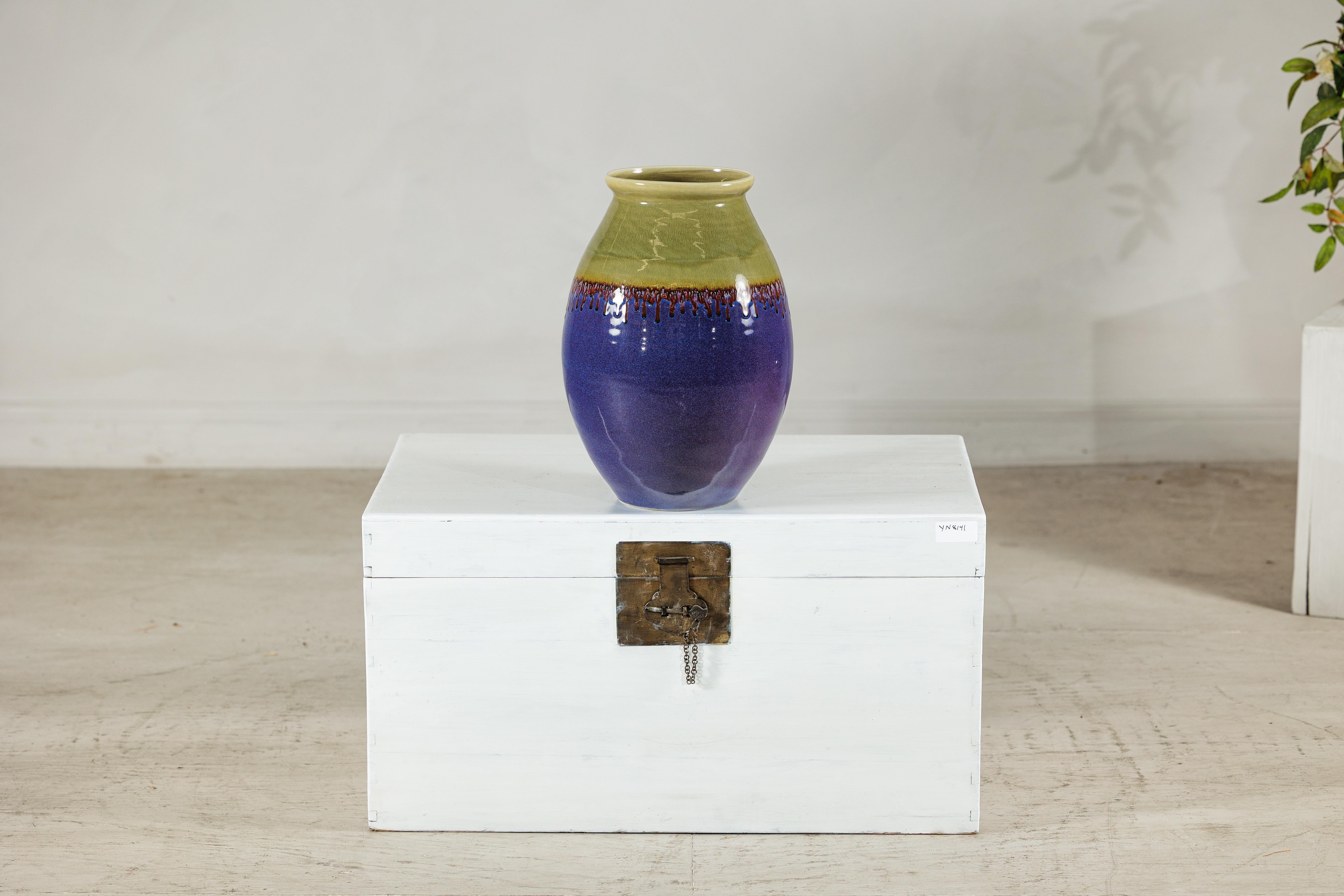 Este jarrón de cerámica ricamente esmaltada muestra un sorprendente contraste de colores y texturas, con una atrevida paleta que va del verde oliva al morado intenso. La superficie se caracteriza por un espectacular vidriado por goteo en marrón