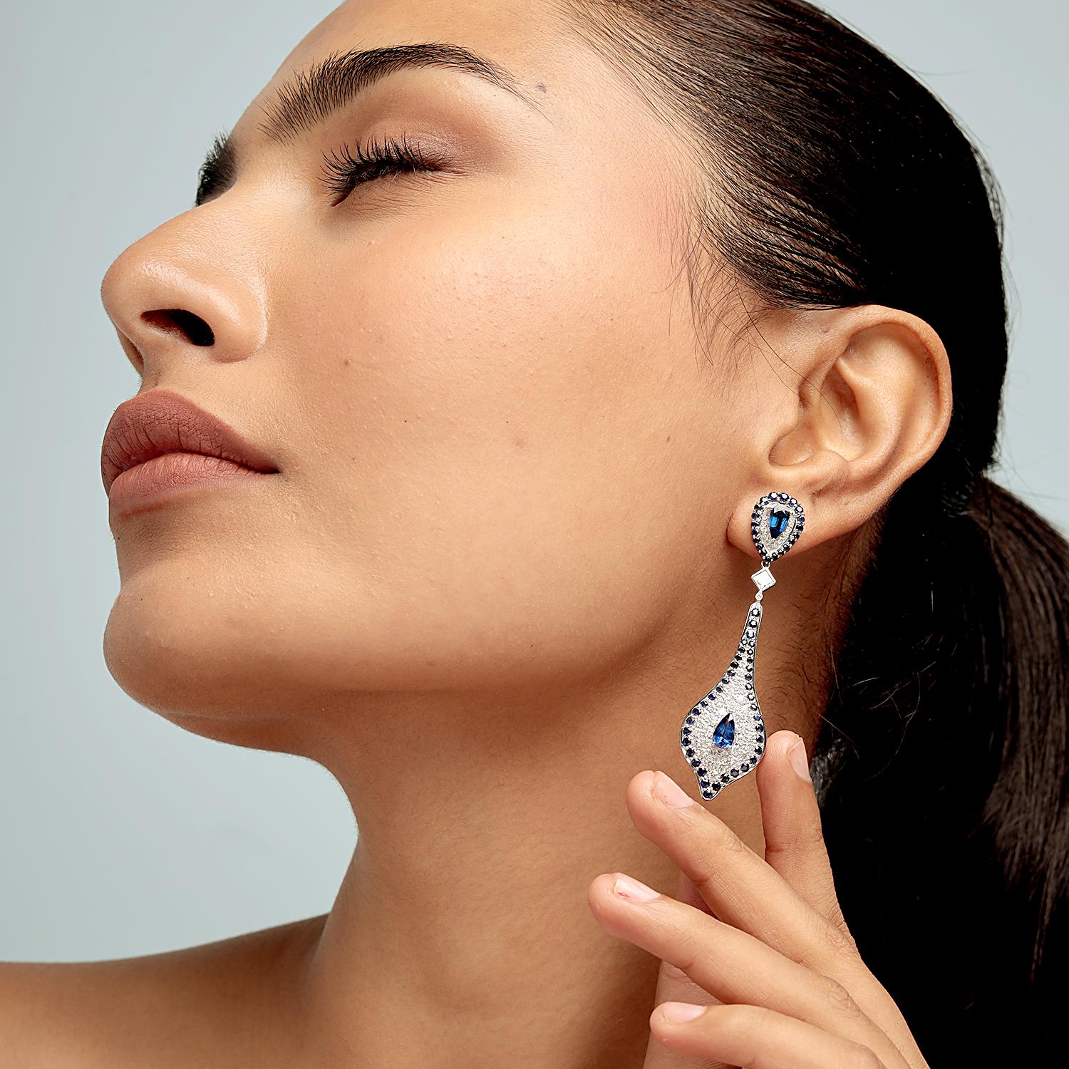 Ces boucles d'oreilles spectaculaires de la marque Artisan présentent 5,71 ct de saphirs bleus profonds et 1,90 ct de diamants brillants, sertis dans 13,609 g d'or blanc 18 carats. La silhouette effilée de 63 x 17 mm associe des saphirs centraux en