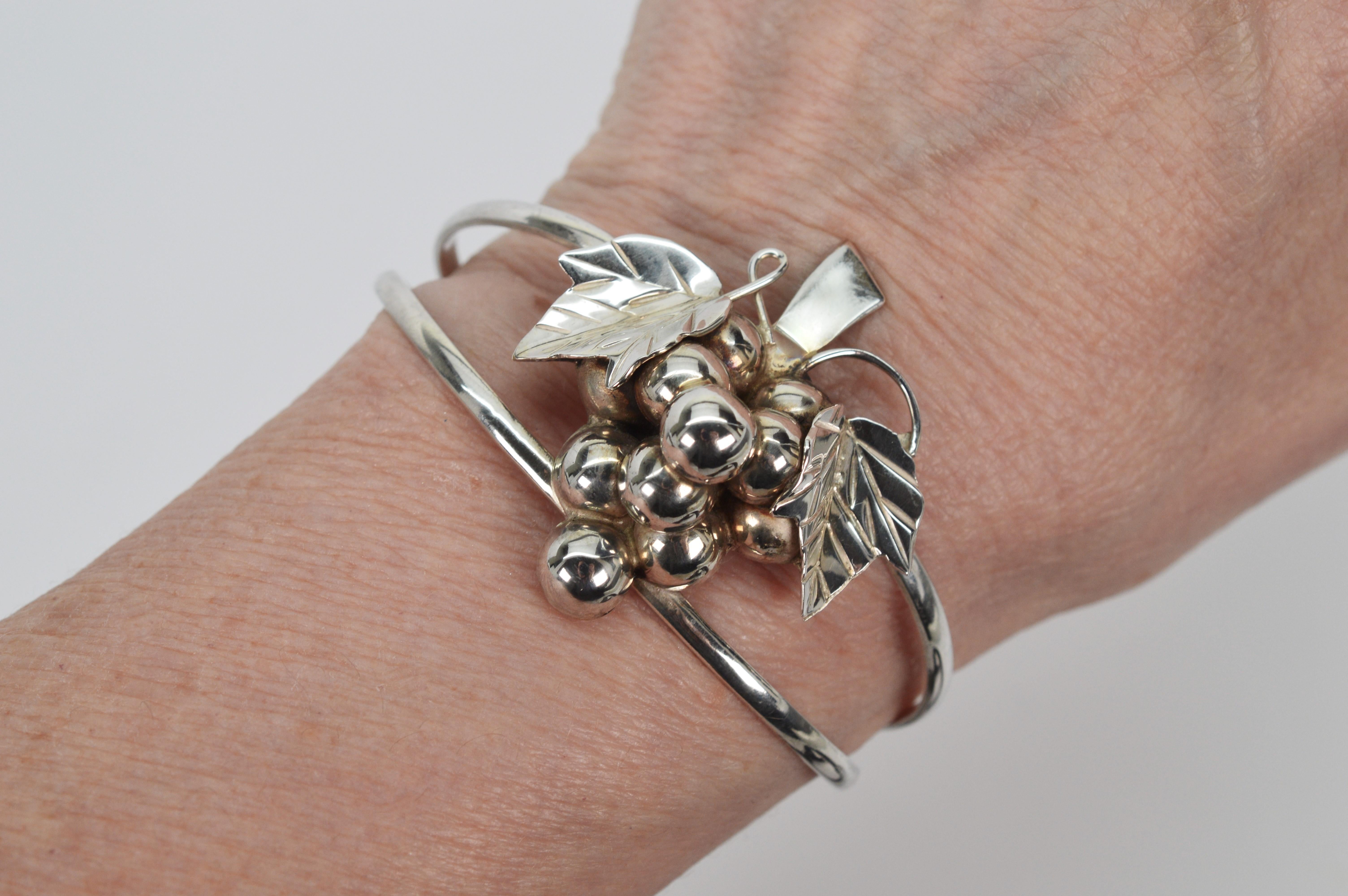Sculptured sterling silver depicts a natural grapevine cluster as the focal point of this artisan .925 sterling silver cuff bracelet. Traditionally a symbol of abundance the hand crafted grapevine cluster applique measures approximately 1-1/2 x