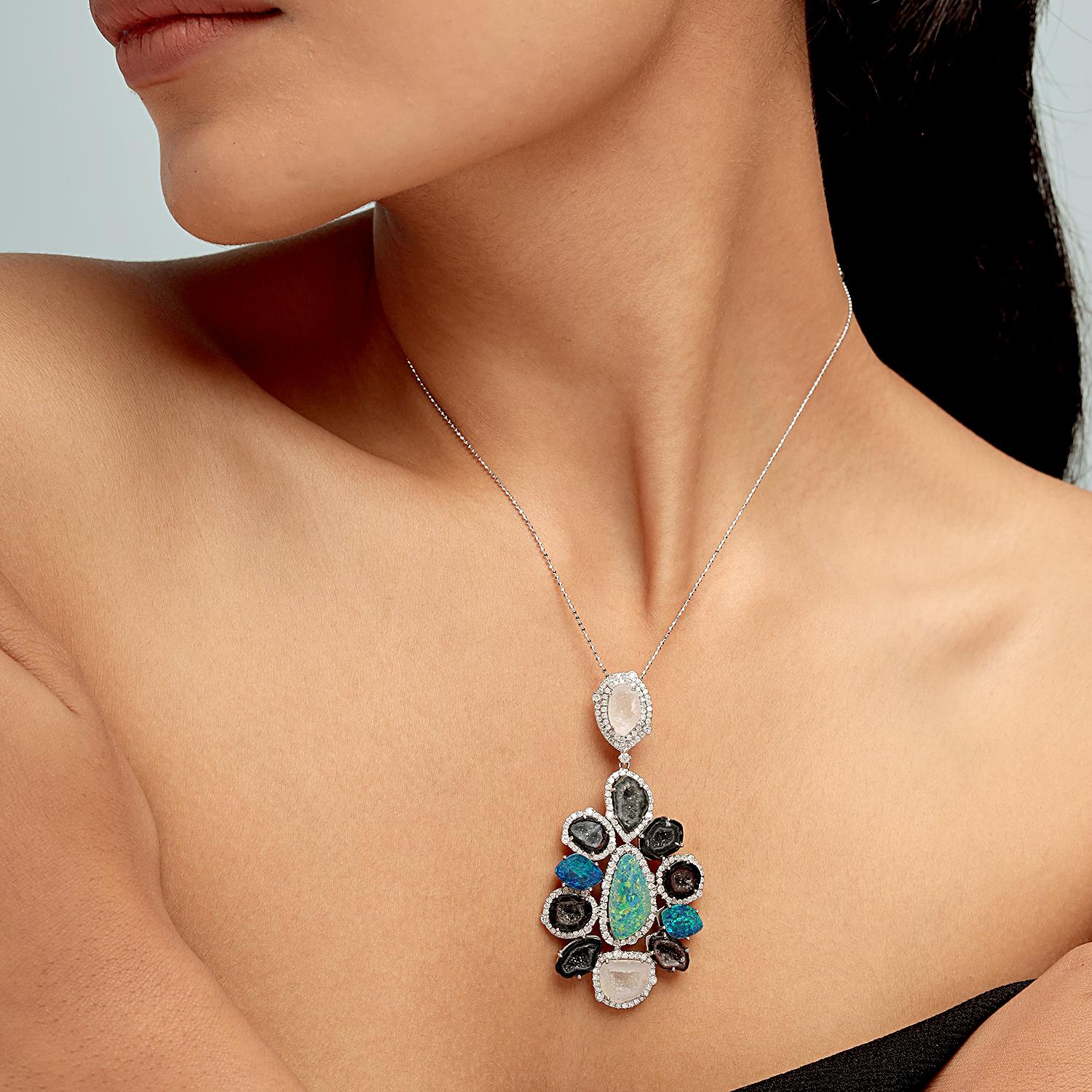 Questa straordinaria spilla pendente di Artisan presenta un mosaico di geodi naturali da 13,50 carati e opali da 5,30 carati, il tutto incorniciato da 1,79 carati di diamanti scintillanti in 9,142 g di oro bianco 18 carati. Il pezzo da 68x35 mm è
