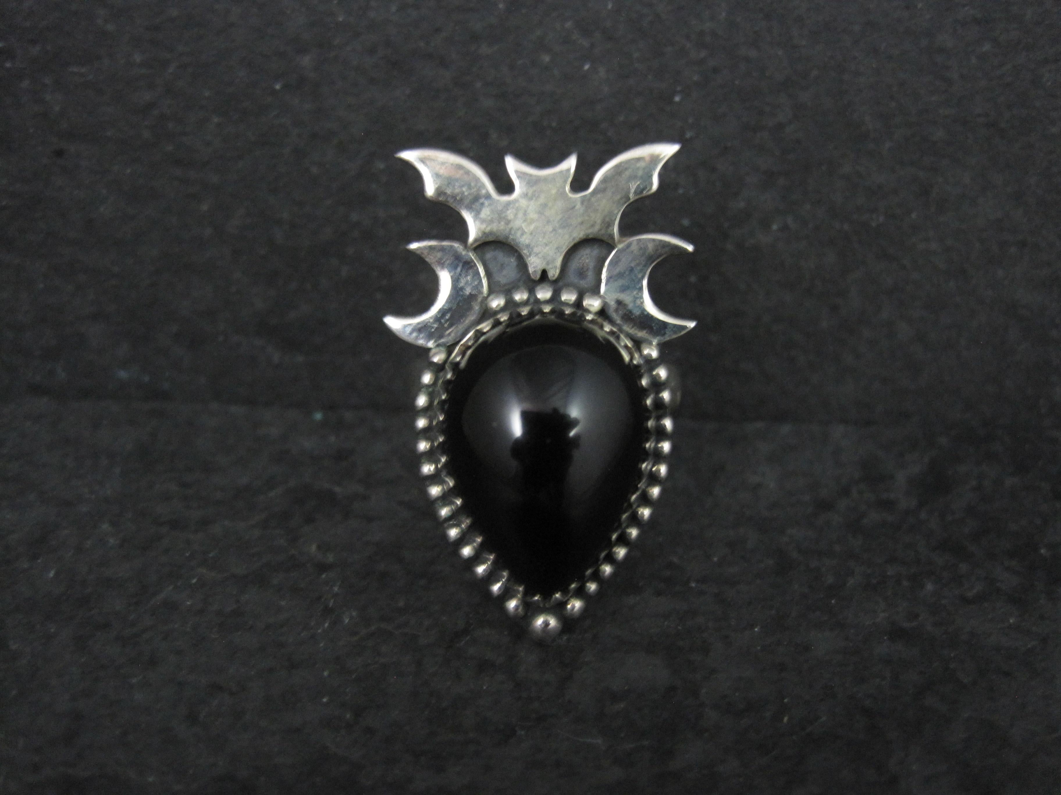 Cette magnifique bague chauve-souris et croissant de lune est en argent sterling avec un cabochon d'onyx noir 13x18 taillé en poire. 
La face de cette bague mesure 13/16 de pouce d'est en ouest et 1 1/4 de pouce du nord au sud.
Il s'agit d'une