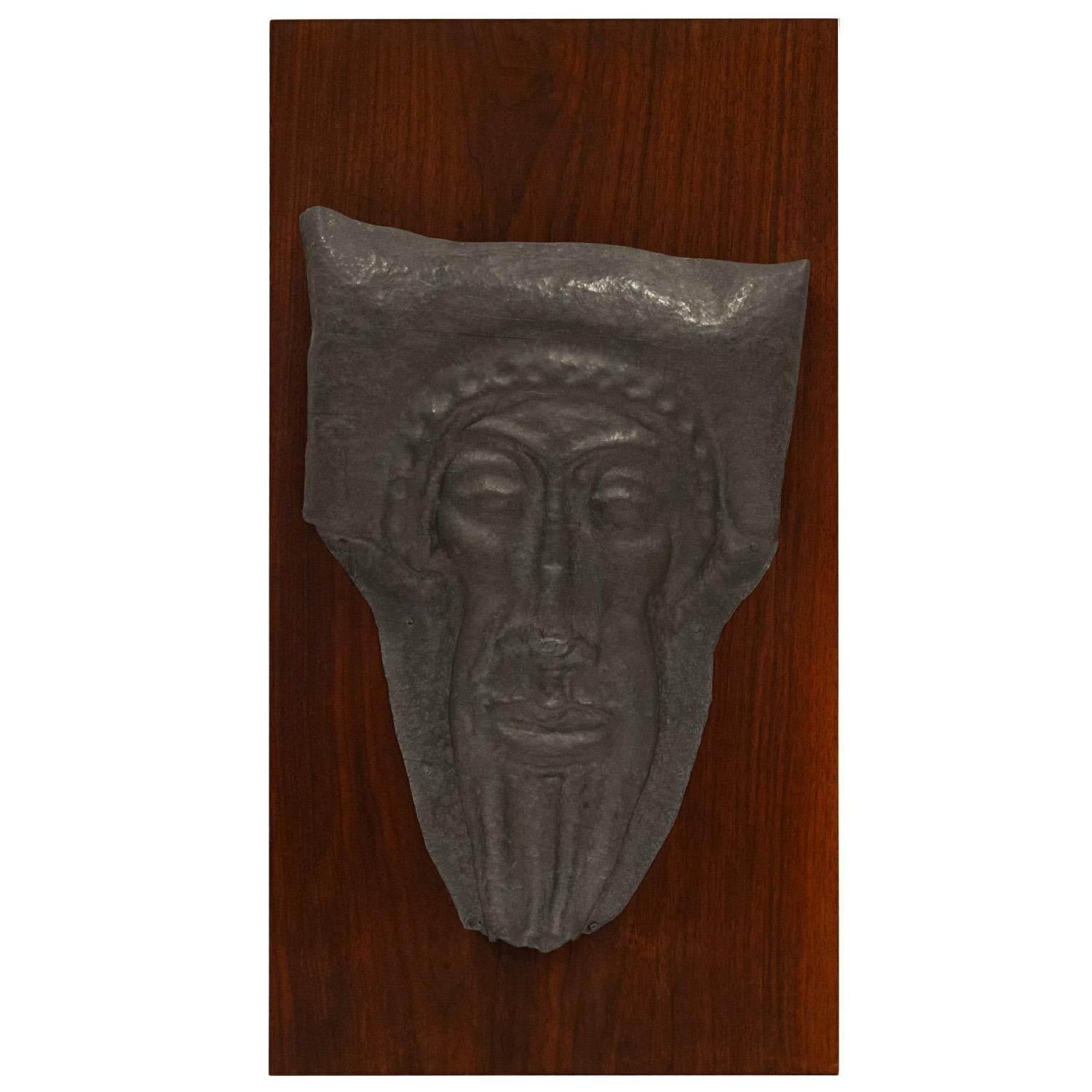 Artisan made face of an ancient Greek man with a laurel wreath molded in pewter and set on a walnut backing, American 1950's. This captivating work is beautifully made.