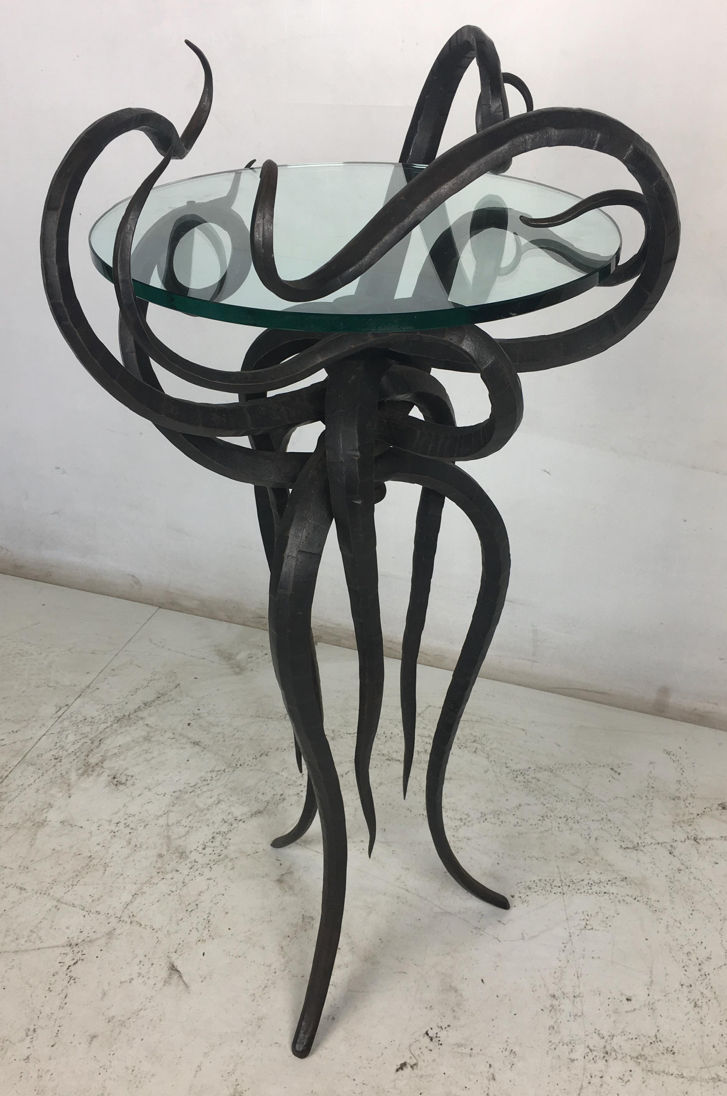 An incredible Artisan wrought iron tour de force is this sculptural side table or plant stand. The twelve tendrils cradle a glass top in its center as it stands on its flowing legs. The workmanship and design on this table is top quality in every