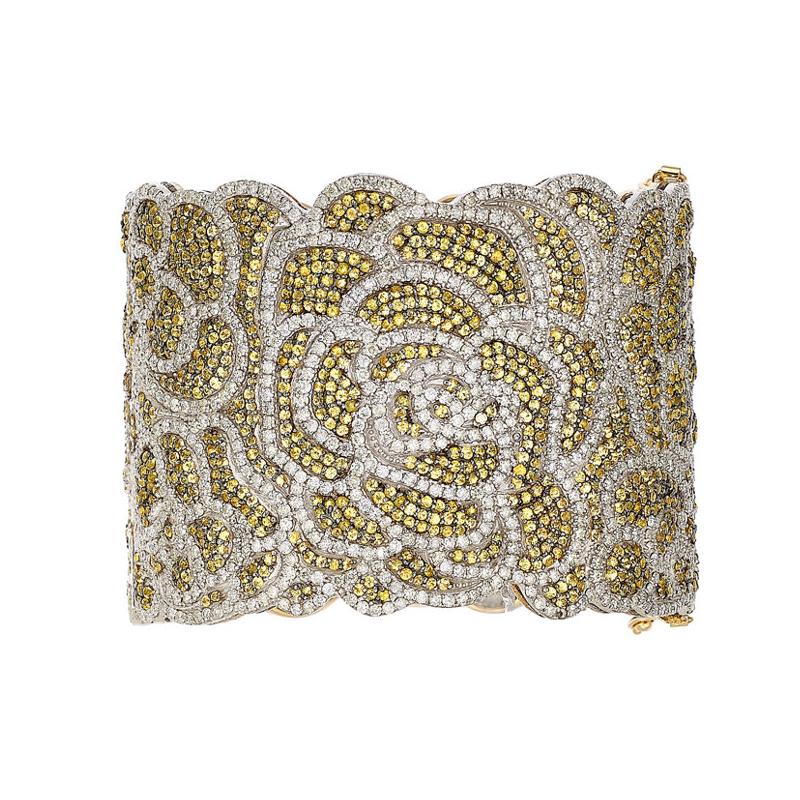 This intricately designed bracelet by Artisan features 23.56 carats of round cut yellow sapphires and 18.18 carats of brilliant cut diamonds in black rhodium which are all pave set to create a flower design. The bracelet is set in 14K white and