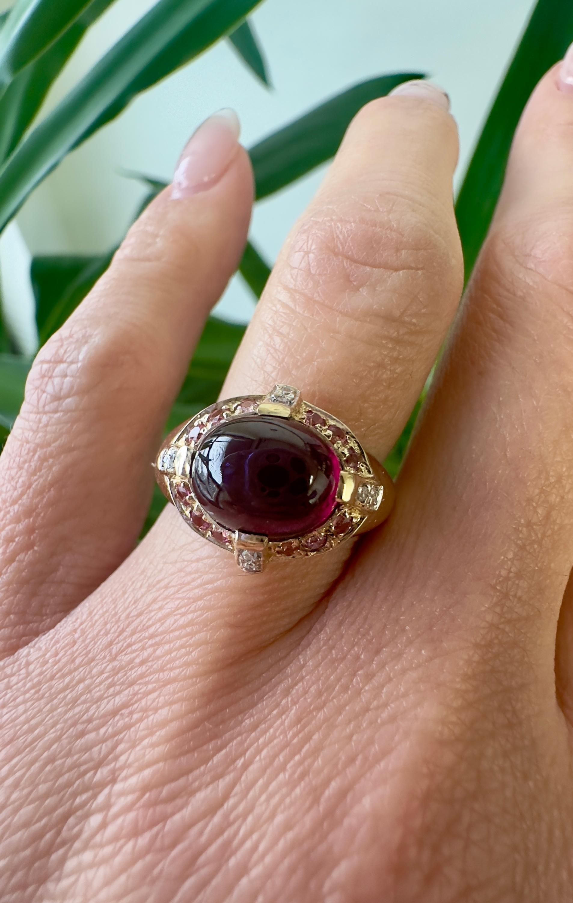 This ornate vintage ring is crafted in 14k yellow gold and spotlights a captivating dark reddish-purple oval tourmaline, weighing 5.21 carats. It's surrounded by a sparkling array of softer pink tourmalines and round single-cut diamonds studded into