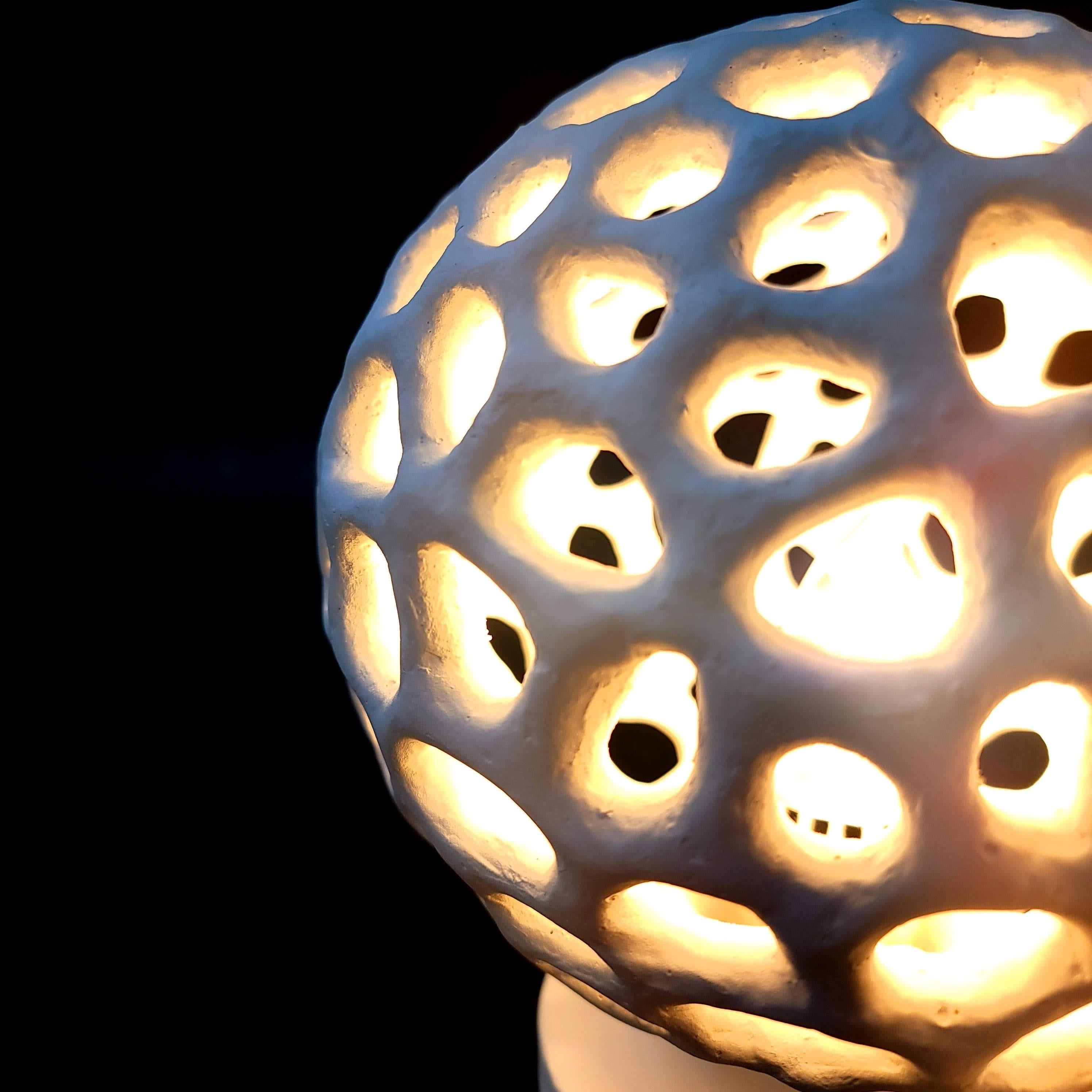 Notre lampe de table d'ambiance Artisanal Voronoi Sphere est une célébration de la beauté complexe de la nature et du charme de la géométrie. Inspirée par les motifs complexes, cette lampe est une œuvre d'art qui fait entrer les merveilles de la
