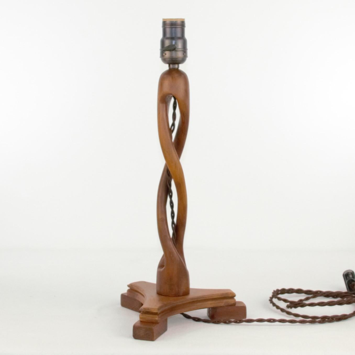 An unusual artisan made wood table lamp, carved out of one piece of wood. The maker painstakingly carved thru the wood creating two distinct twists that rise from the base and finish in a soft round top. We have waxed the wood to help preserve the