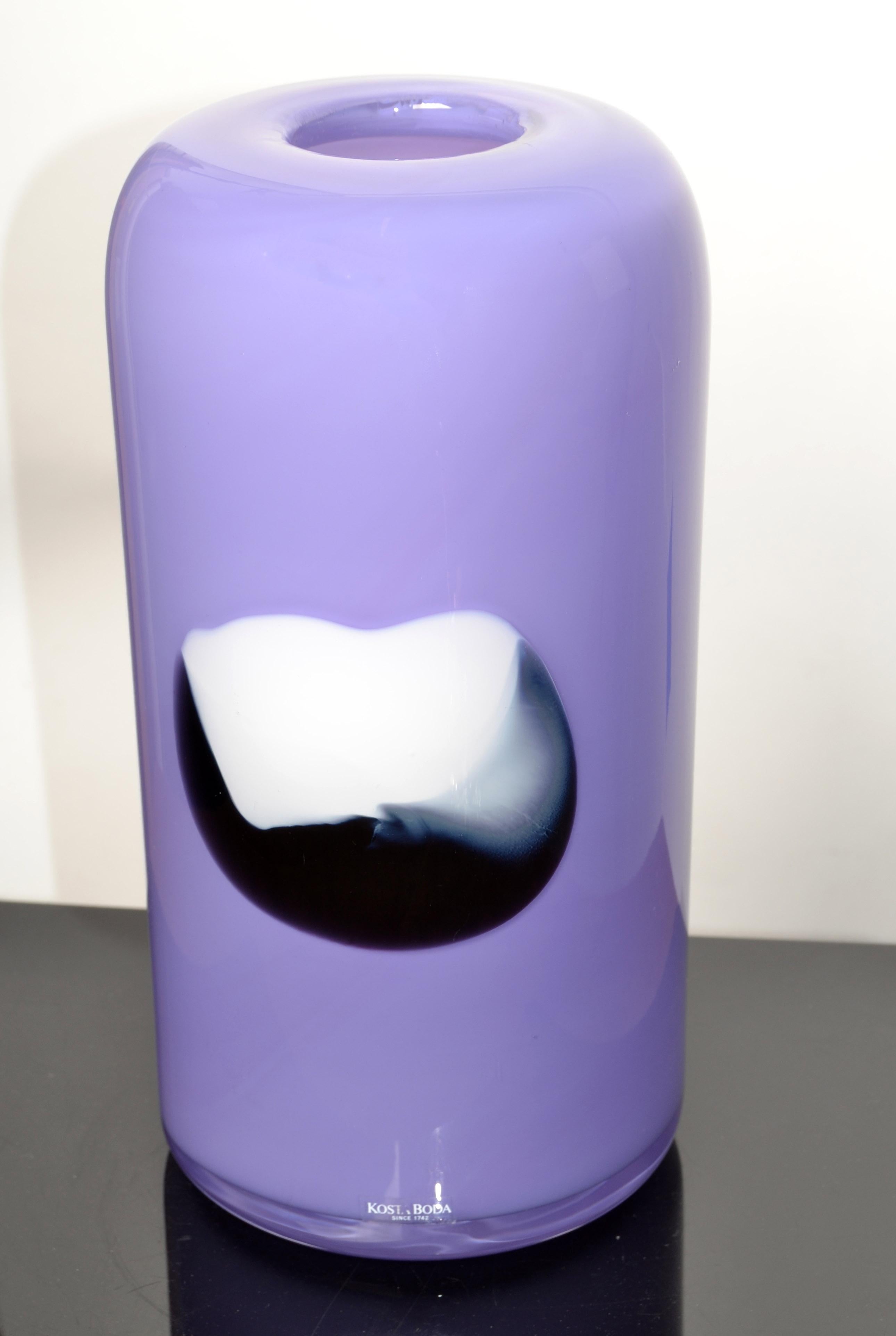 Hellviolette Zylindervase aus Kunstglas, handgefertigt von Gunnel Sahlin mit abstraktem schwarz-weißem Zentrum für Kosta Boda, Schweden.
Gunnel Sahlin war von 1986-2005 bei Kosta Boda tätig, dieses Stück ist um 1990 entstanden.
Mit einer klaren
