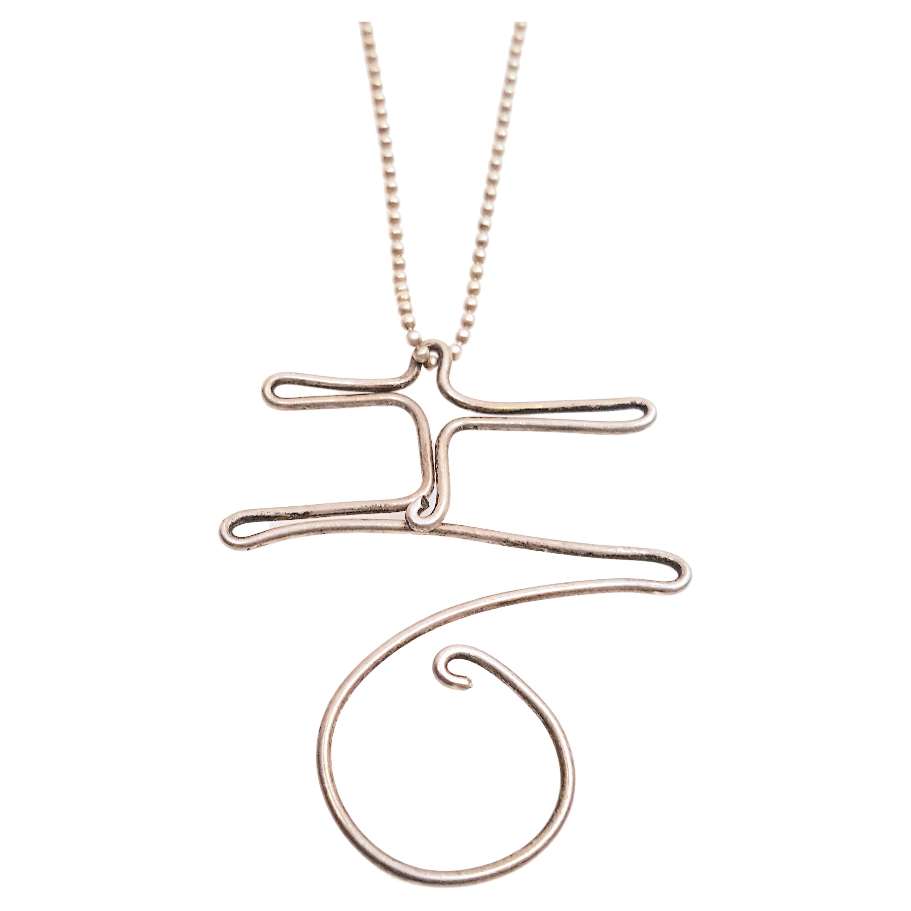 Like Alexander Calder's handmade wire jewelry since 1929, whose smallest one-of-a-kind sculptural subjects ranged from aerial acrobats and dancers to monograms with letters representing a friend, this modern minimal sterling-silver wire pendant was