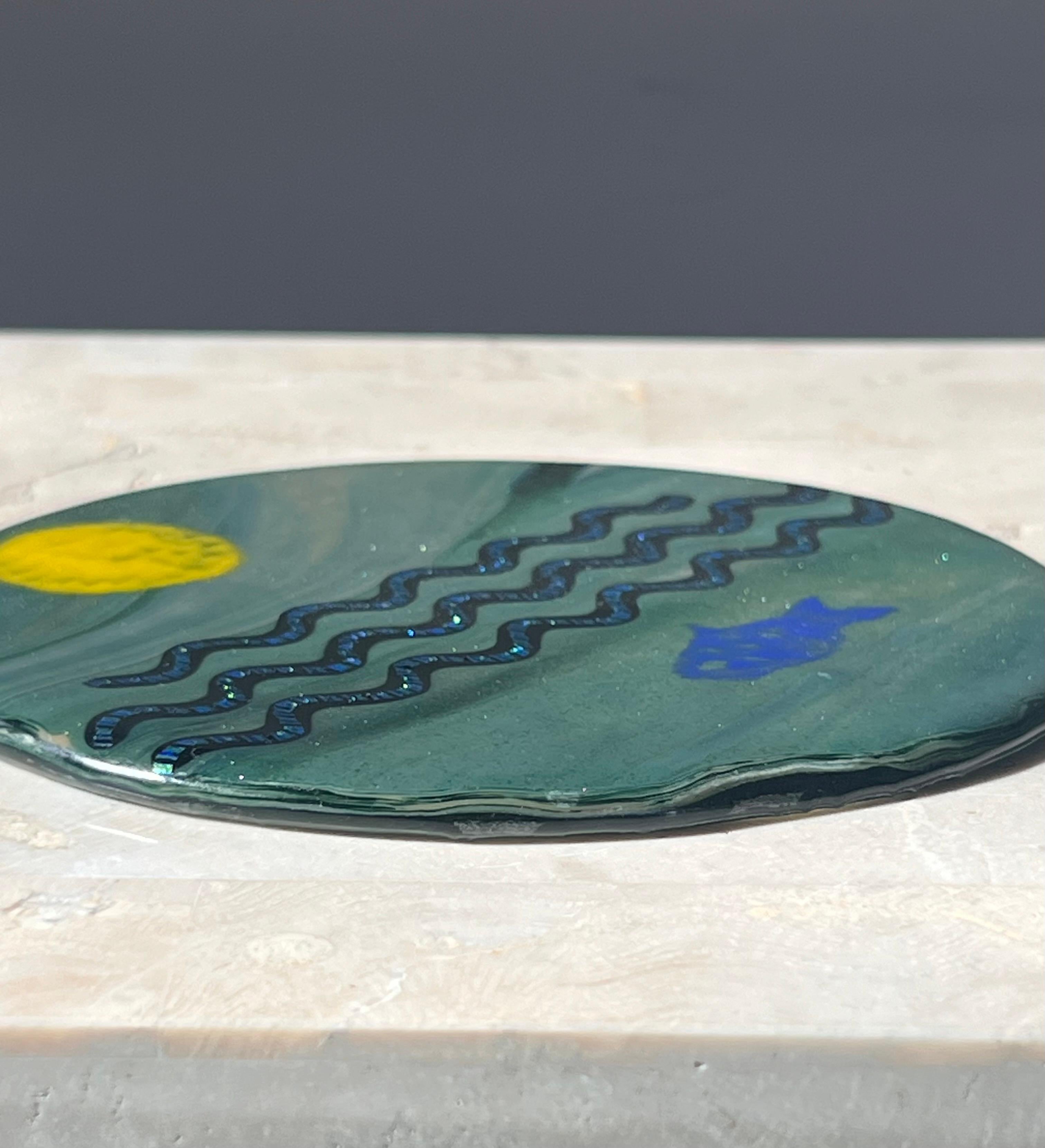 Placa de vidrio artístico con motivo submarino, probablemente de finales del siglo XX. Muestra tonos de verde azulado, azul real, regaliz y limón, y con un brillo que recuerda a la bioluminiscencia. Se puede utilizar como pisapapeles l, elemento