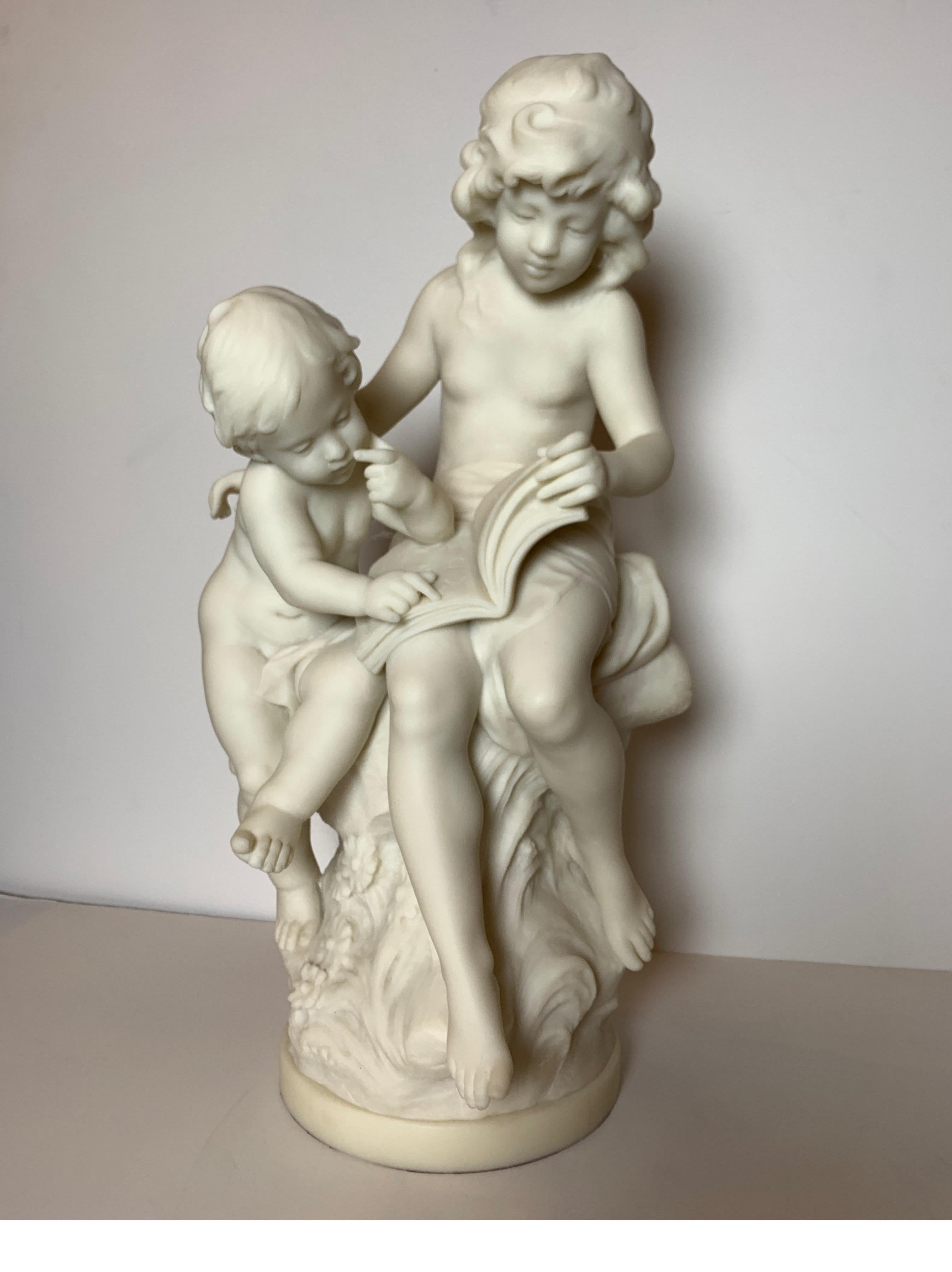 Solid marble sculpture of siblings reading on circular base. The sculpture with two children sitting on a tree stump with book, signed on base Auguste Moreau, 1837-1917.