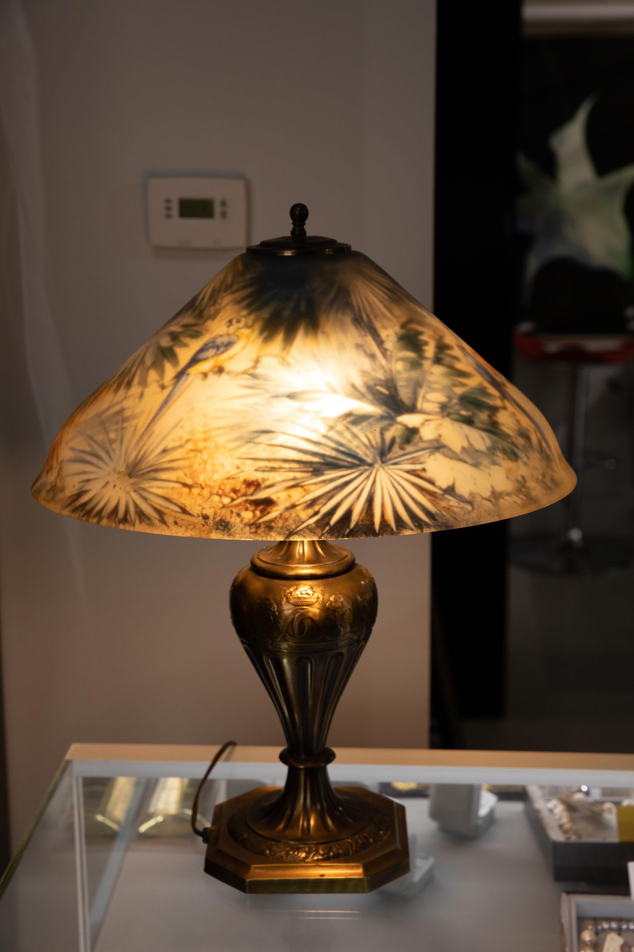 Artist signed Pairpoint reverse painted table lamp with a jungle motif depicting parrots. The base is signed Pairpoint and the shade is initialled H.F.. The glass is in great condition. Pairpoint Manufacturing Company was founded by Thomas J.