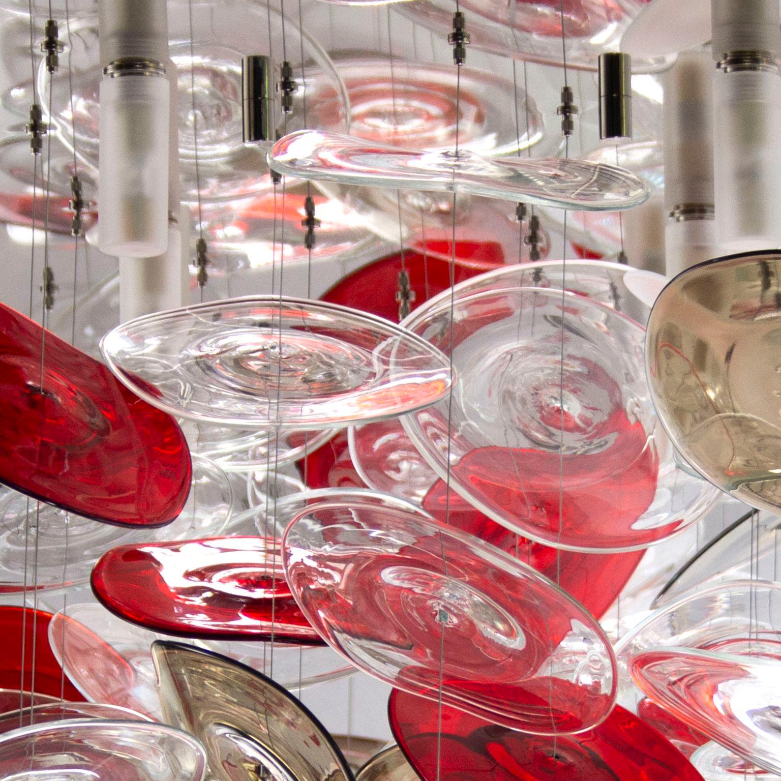 Hydiscuss is an artistic ceiling composition with disks in red, transparent, white, moka Murano glass.
Abandoning the concept of lighting only, the artistic chandelier Hydiscus wants to be an architectural installation that stands out for its