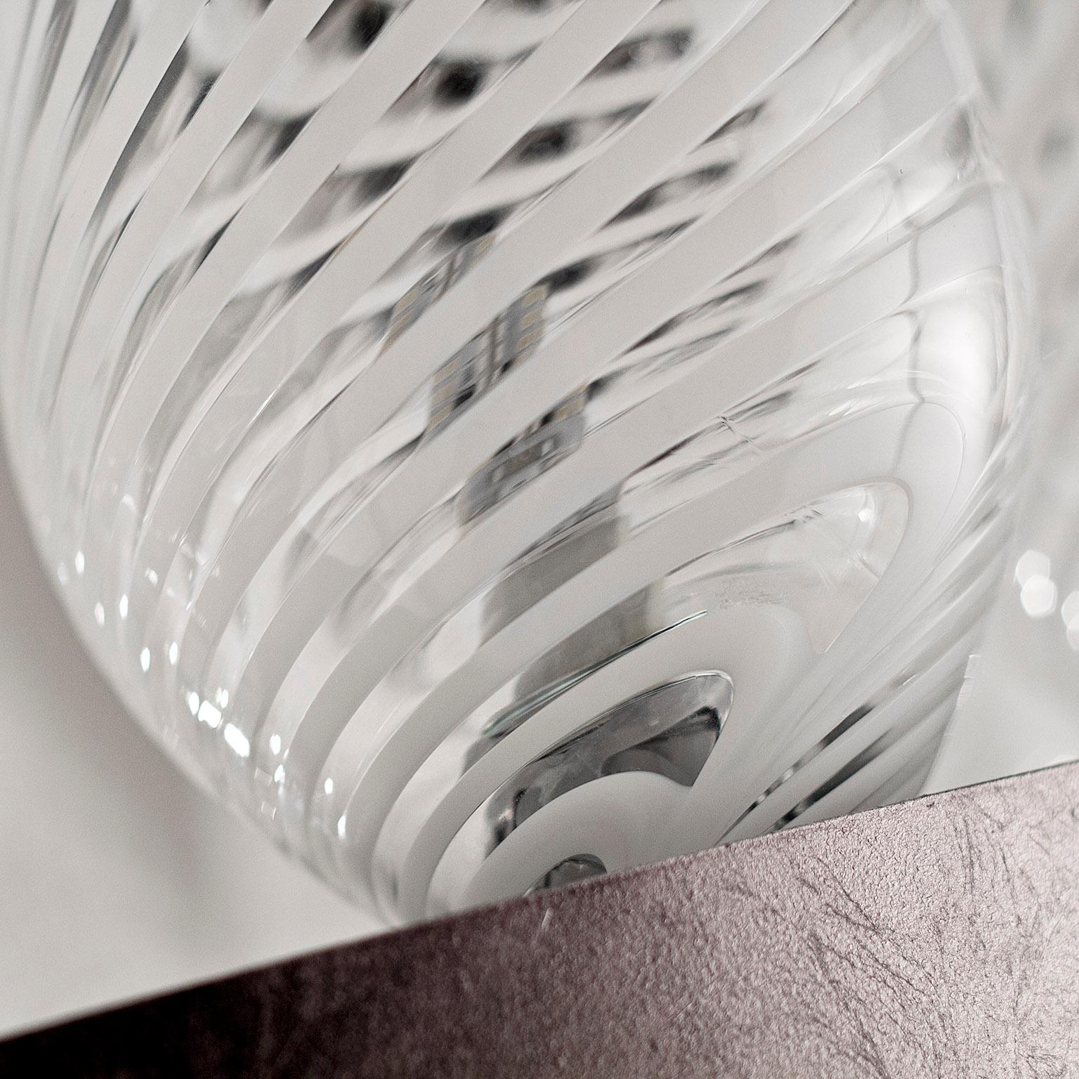 La forma del lampadario in vetro Pasha ricorda quella di una corona ma, al posto delle gemme, sono stati montati degli elementi decorativi in vetro soffiato. Un design moderno combinato con forme classiche caratterizza questo lampadario, le cui