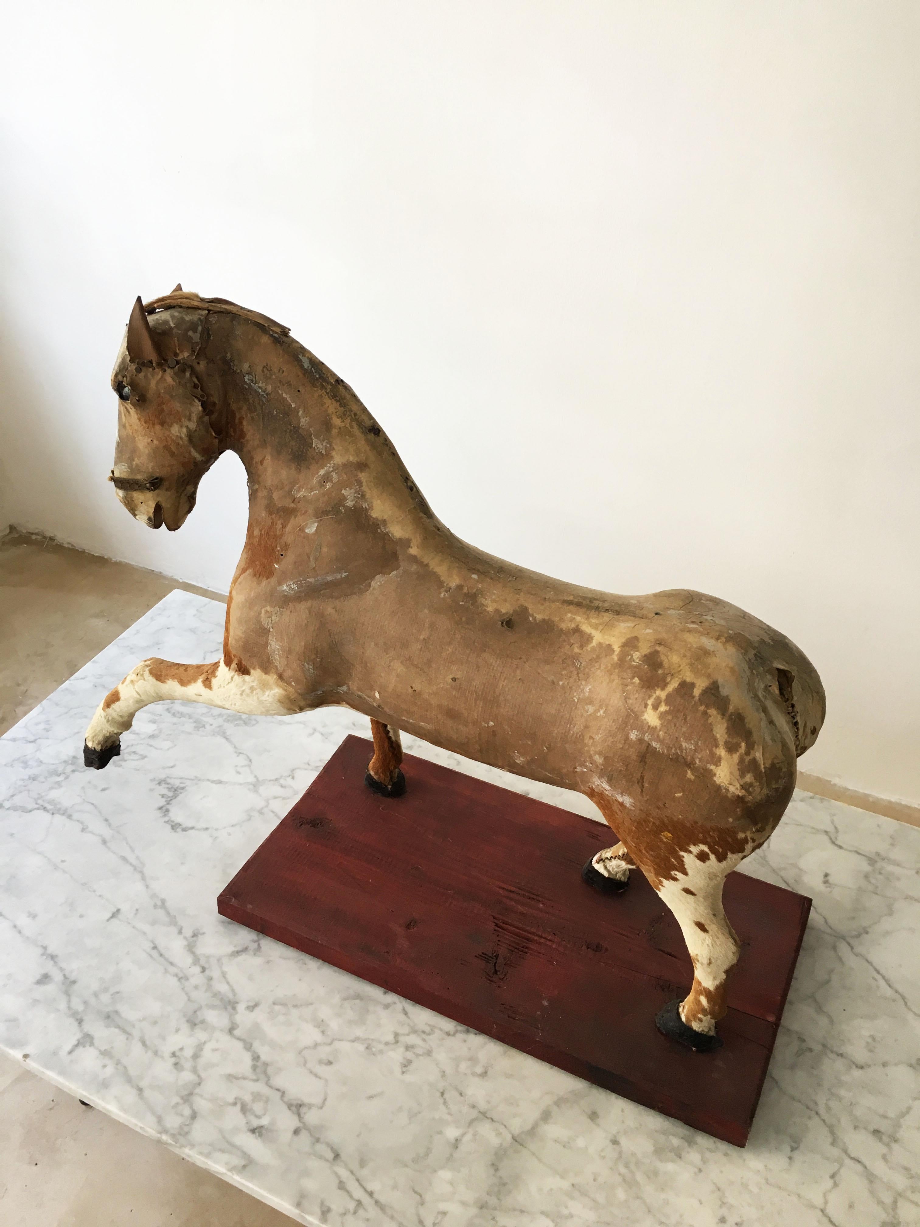 A stunningly beautiful decorative horse model object, France, early 20th century. Standing on a painted wood base, the finely sculpted horse model might have been a children toy in it's past life. We love the weathered look and feel, giving it an