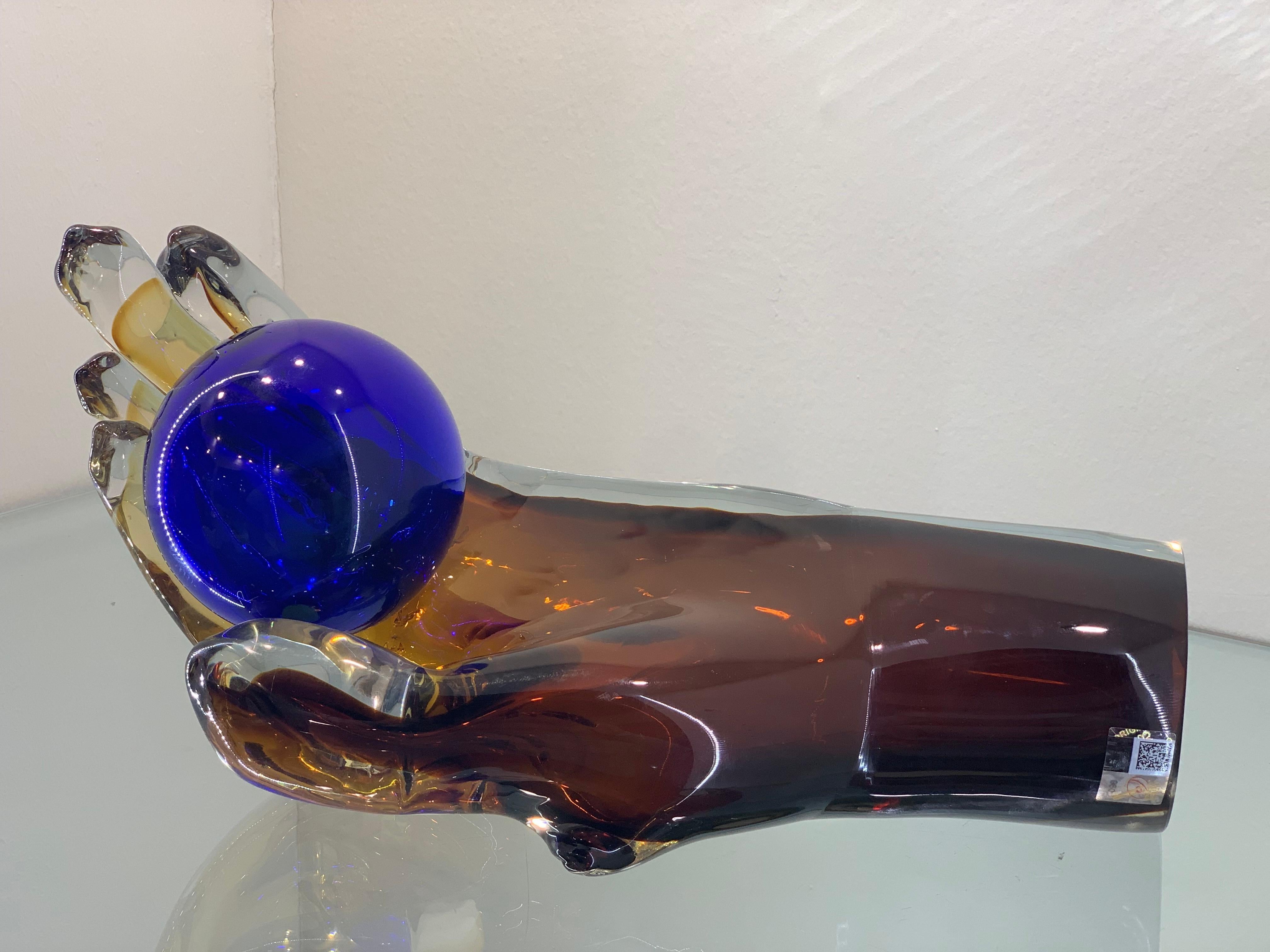 A modern Murano glass sculpture portraying an epic hand .
Dark Amber with blue Sphere.