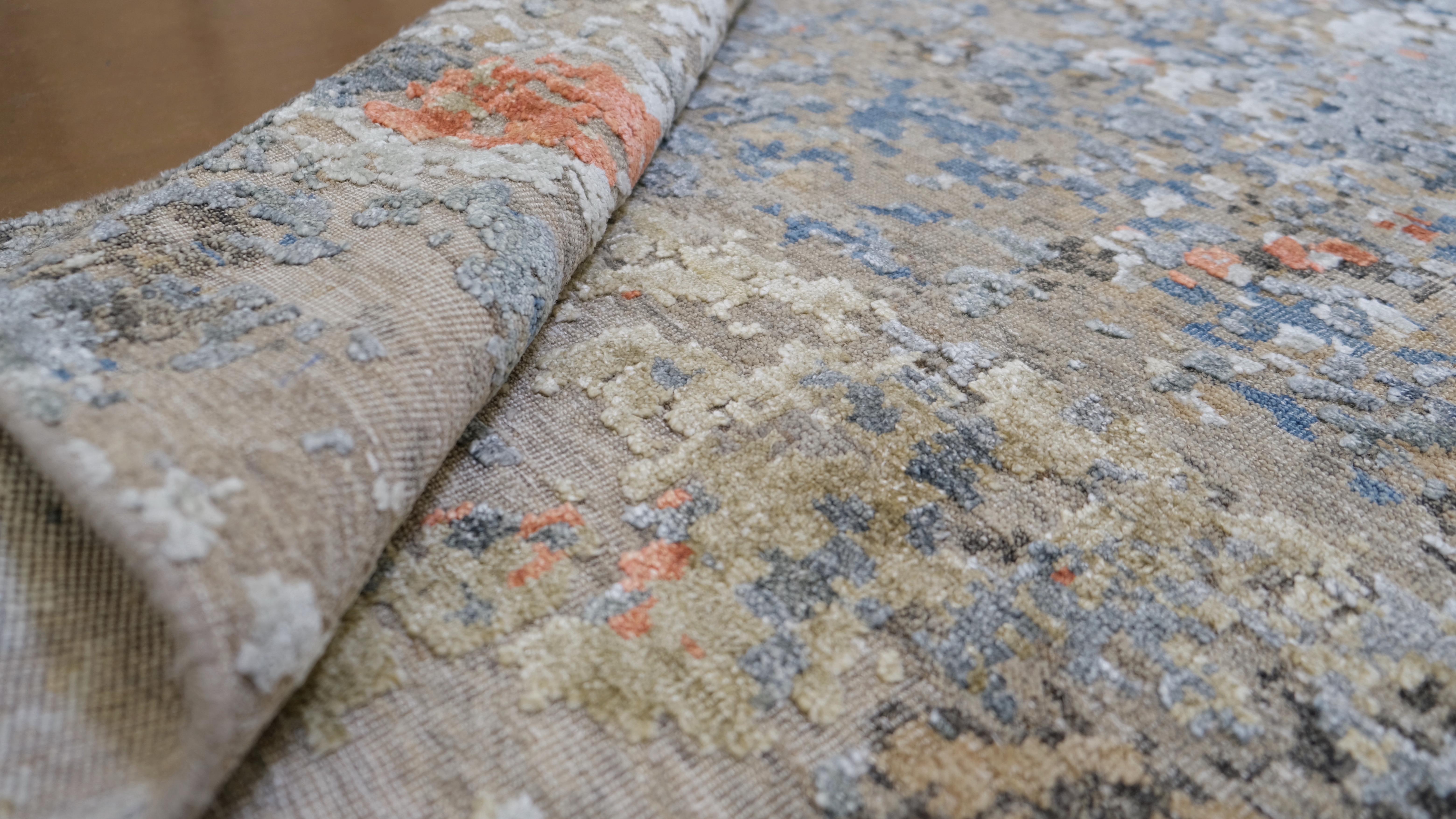 Introduci un tocco artistico nei tuoi interni con questo tappeto in lana e bambù annodato a mano. Questo splendido pezzo presenta un accattivante disegno astratto che mescola vibranti tonalità di blu, arancione, beige e grigio per creare un