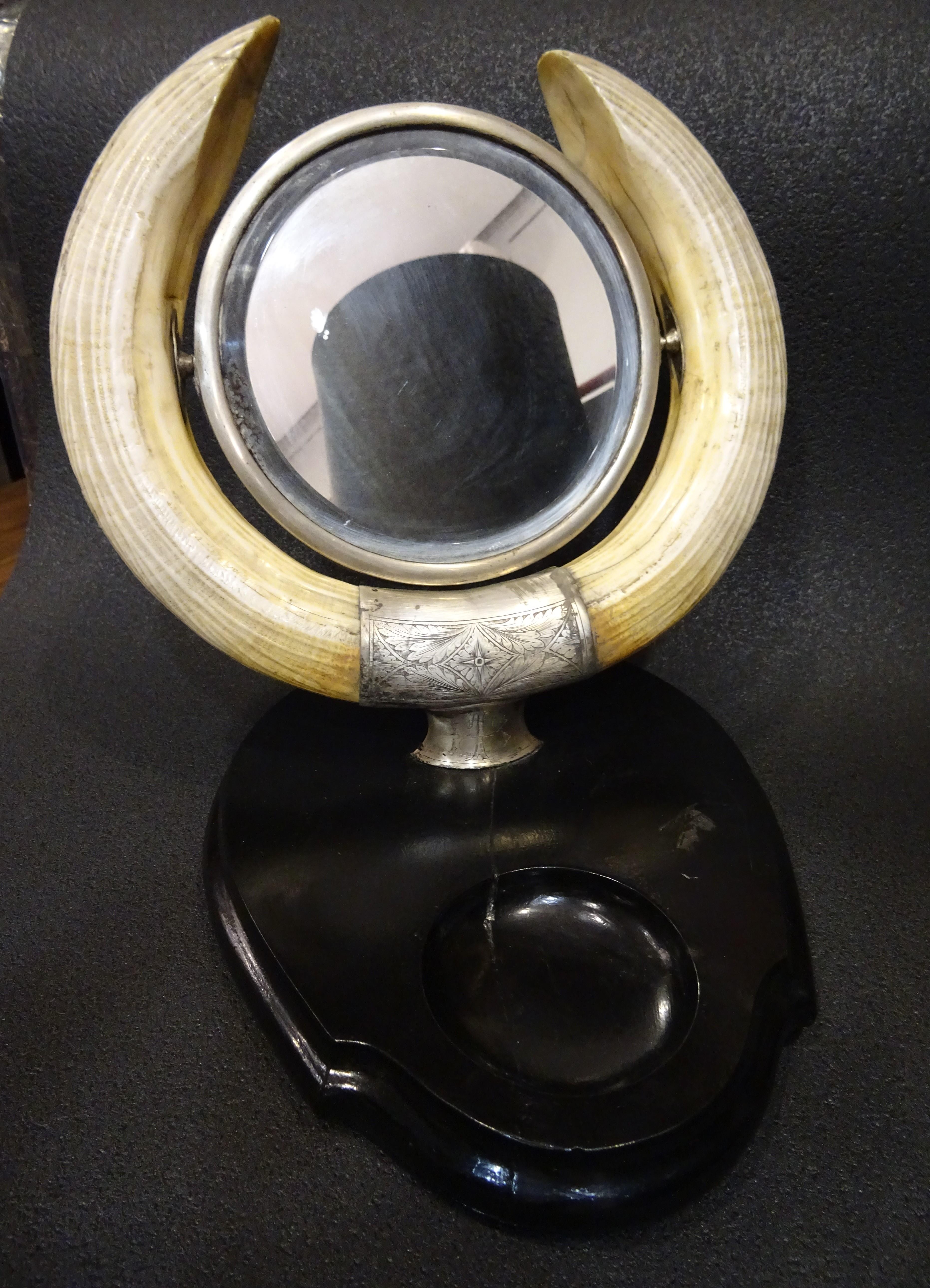 Outstanding vanity mirror, French Art Nouveau, circa 1900. Two hippo horns hold a tilting mirror enriched and decorated with silver, there are some initials in the front of the mirror.
The base is in ebonized wood with a hole to let the small