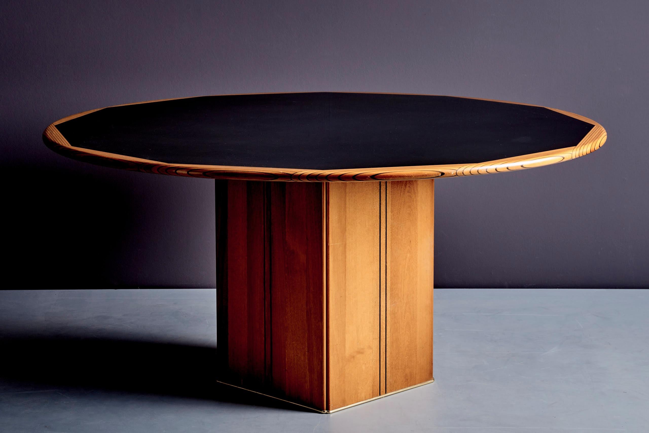 Elegante mesa de comedor redonda de la serie Artona, diseñada por Afra & Tobia Scarpa para Maxalto en la década de 1970. La mesa presenta un tablero lacado en negro con una llamativa incrustación de madera, que descansa sobre una base de pedestal