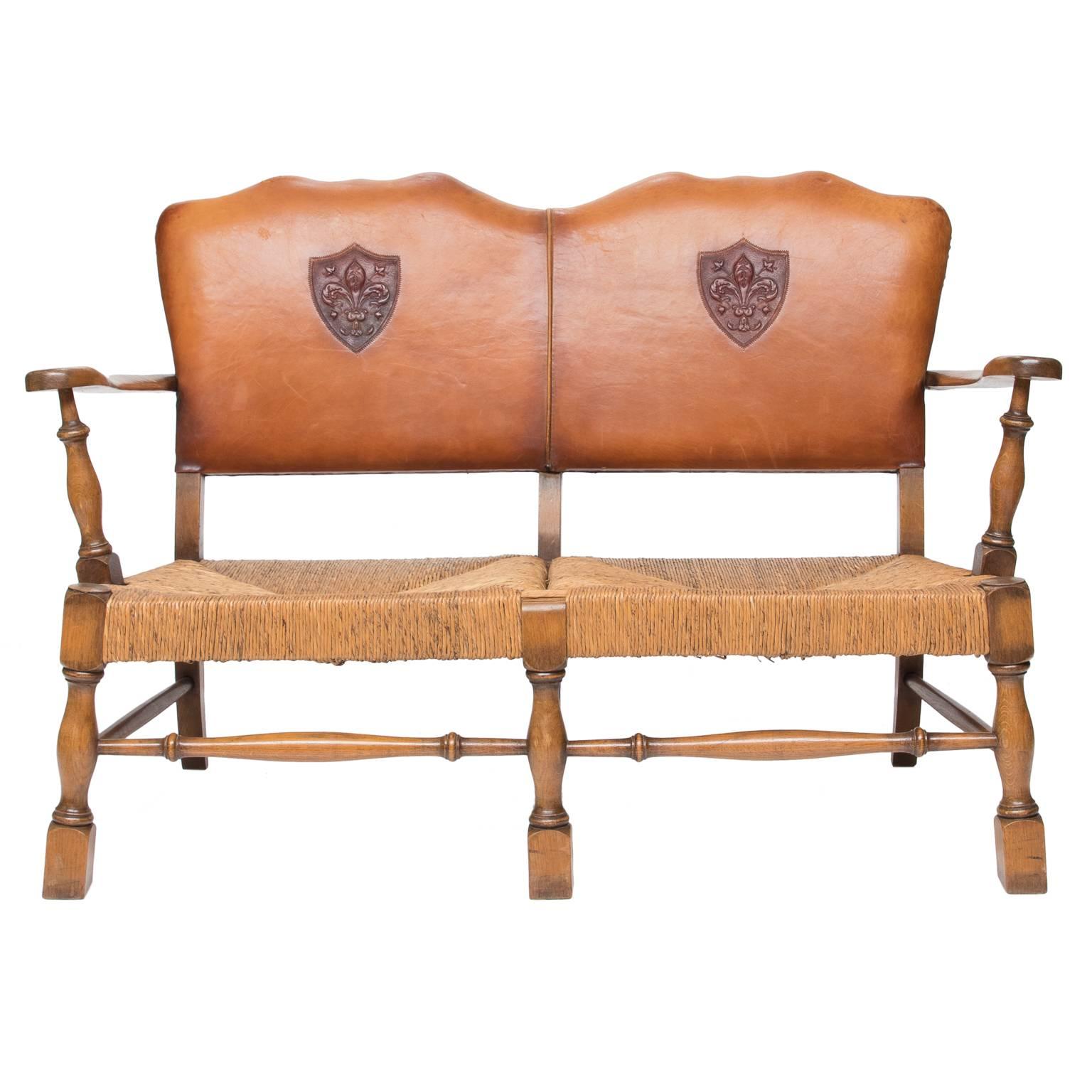 Vintage Arts & Crafts style French settee with two armchairs. This suite is made of French oak wood, rush seat (the rush is in very good condition) and embossed leather backs with shaped crest. There is enough space to have a cushion made for the