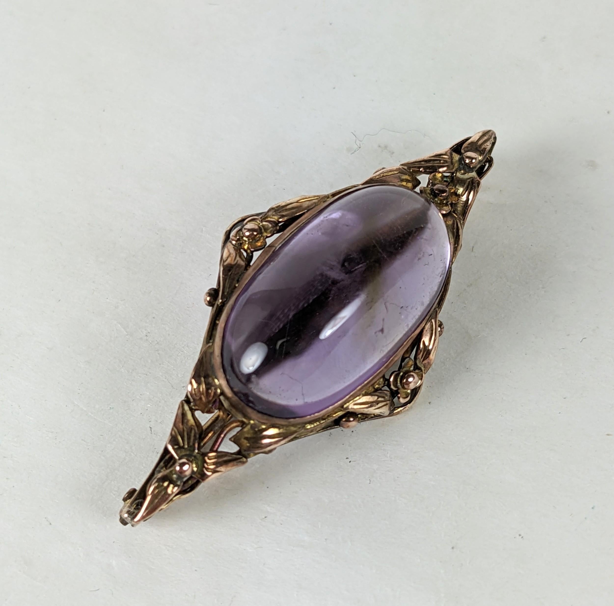 Arts and Crafts Amythest Cab Floral Brooch in low carat pink gold from the early 20th Century. Completely hand made with floral and leaf border around a large oval cab amythest. 1900 USA or UK.  1.75