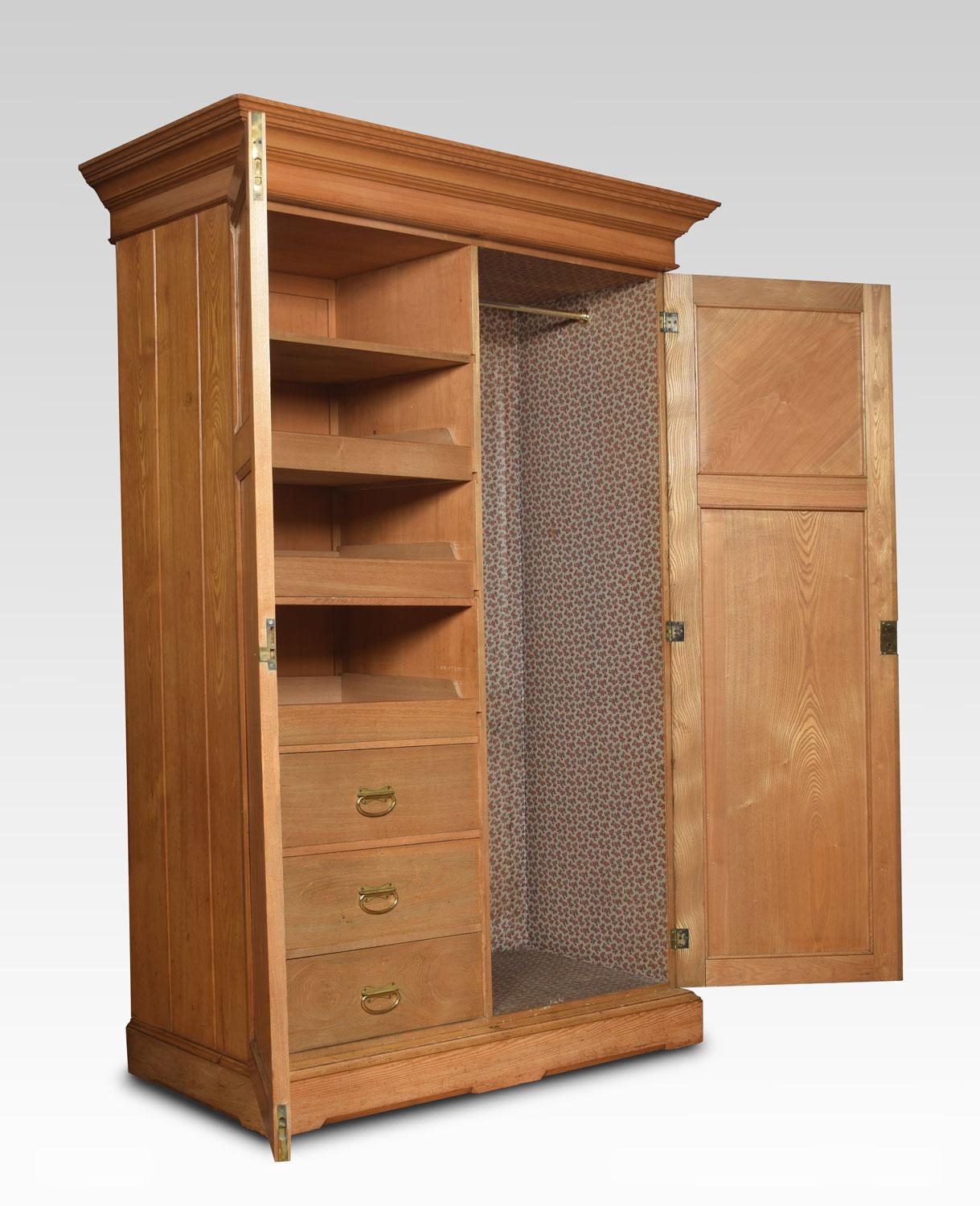 Golden ash combination wardrobe, The moulded cornice above two large panelled doors opening to reveal a fully fitted interior comprising of sliding trays and drawers the opposing side with hanging space. All raised up on plinth