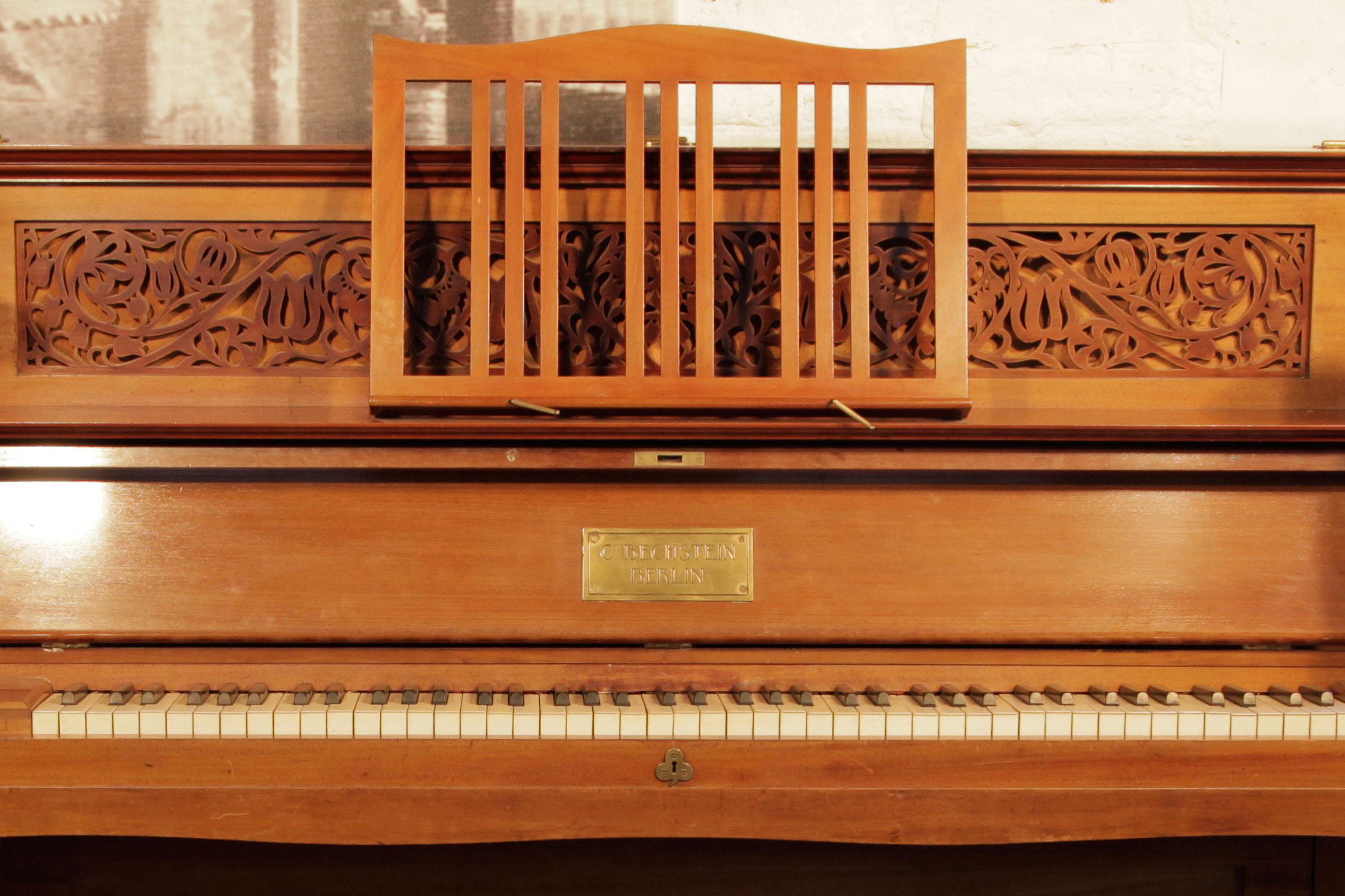 Arts and Crafts style, 1898, Bechstein upright piano with a walnut case. Cabinet features a cut-out, fretwork panel in a stylised floral design. Cabinet features sizeable, brass hinges on the fall and top lid with trefoil embellishments. Part of the