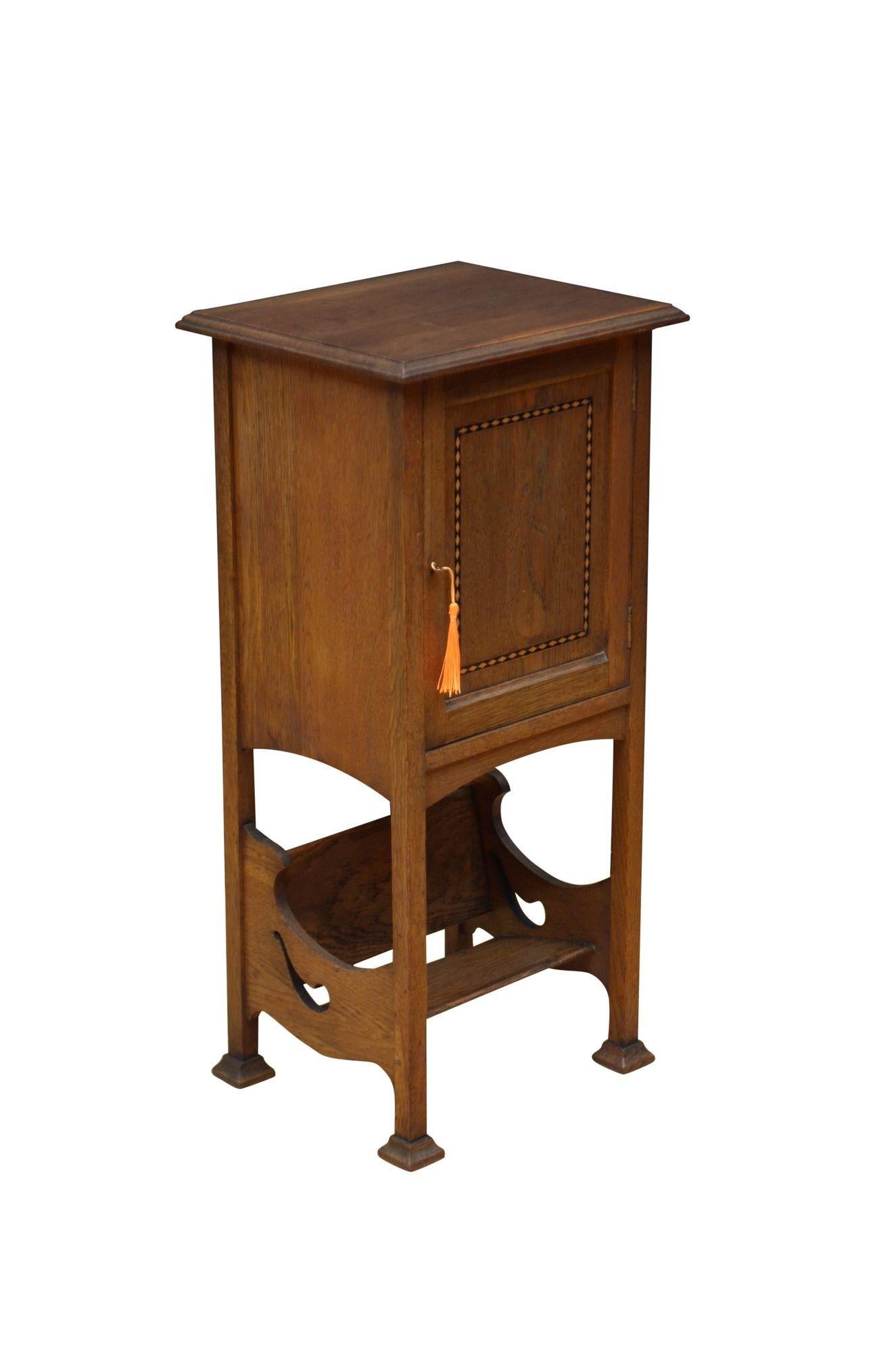 P0299 Stylish Arts and Crafts oak bedside cabinet, having single plank top with moulded edge above a panelled and inlaid cabinet door fitted with original working lock and a key and enclosing shaped shelf and pipe compartments on the doors (can be