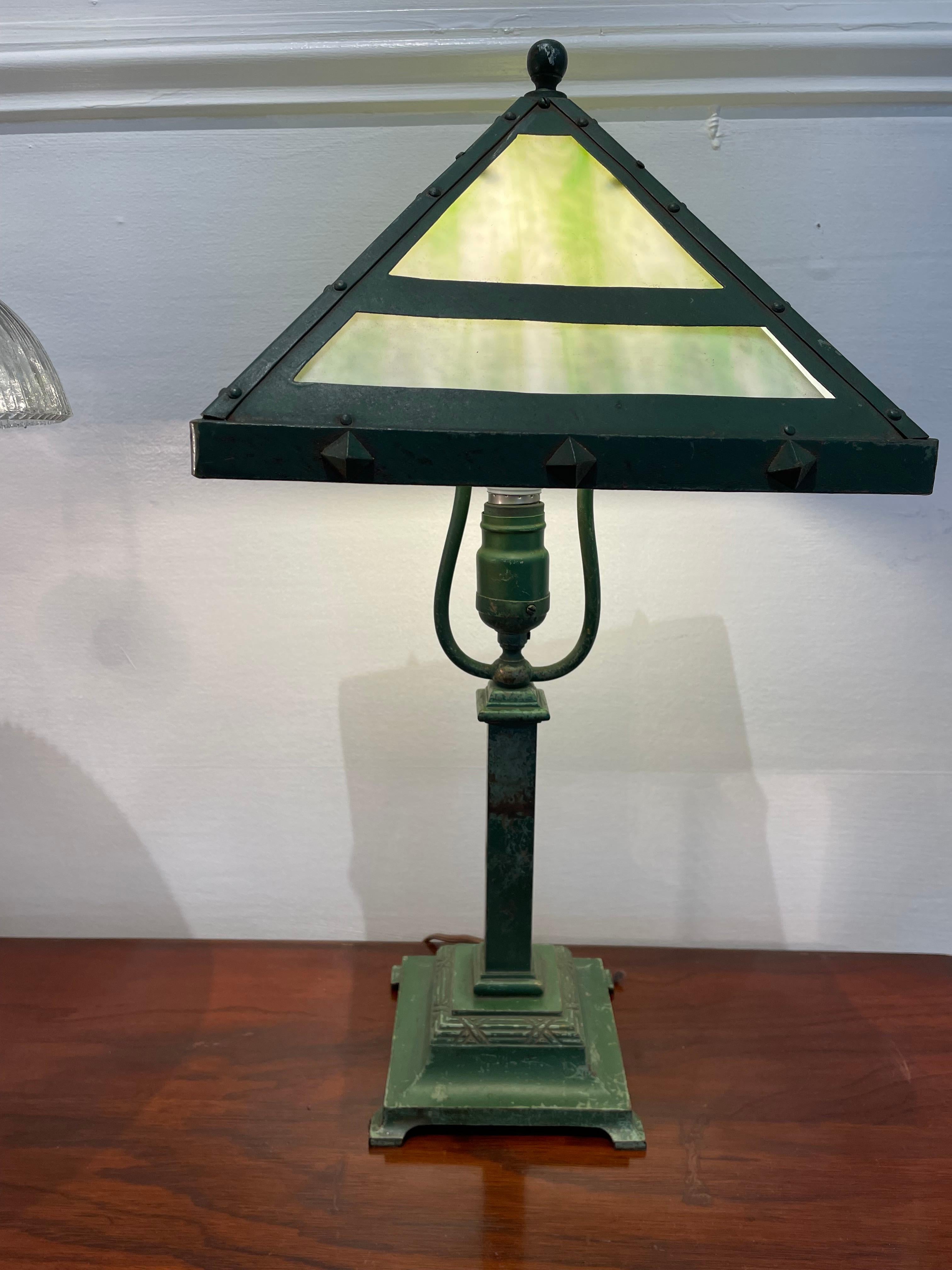 A lovely Bradley and Hubbard table or desk lamp from the Arts and Crafts period. American. An iron base with the original green paint, which also appears along the frame of the shade. The shade is adorned with raised stars giving the lamp a slightly