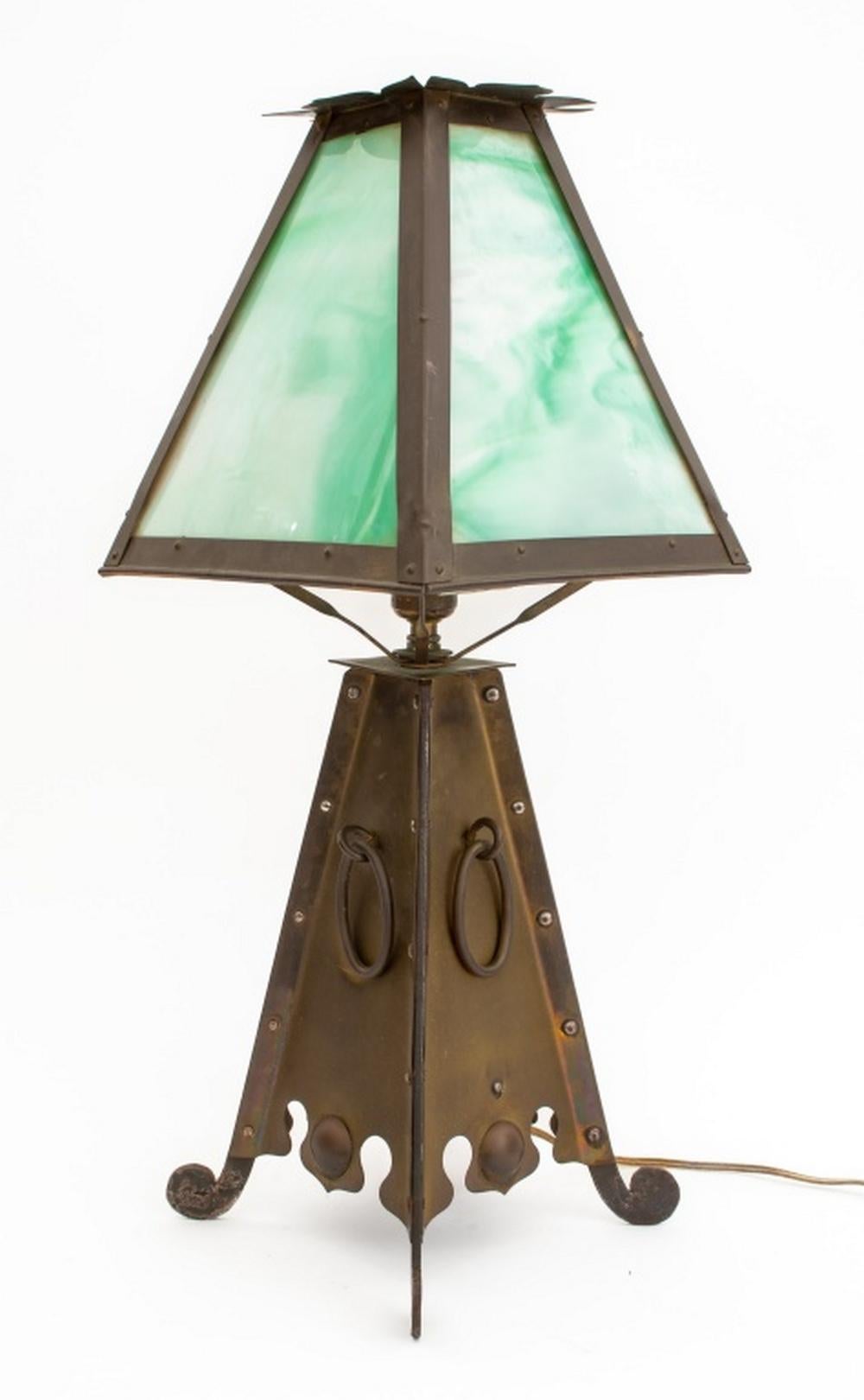 Lampe de table Arts and Crafts en laiton et en fer, début du 20e siècle, avec un abat-jour en verre de scories vertes et blanches, des poignées ovales en forme d'anneau sur quatre pieds à volutes. 23.5