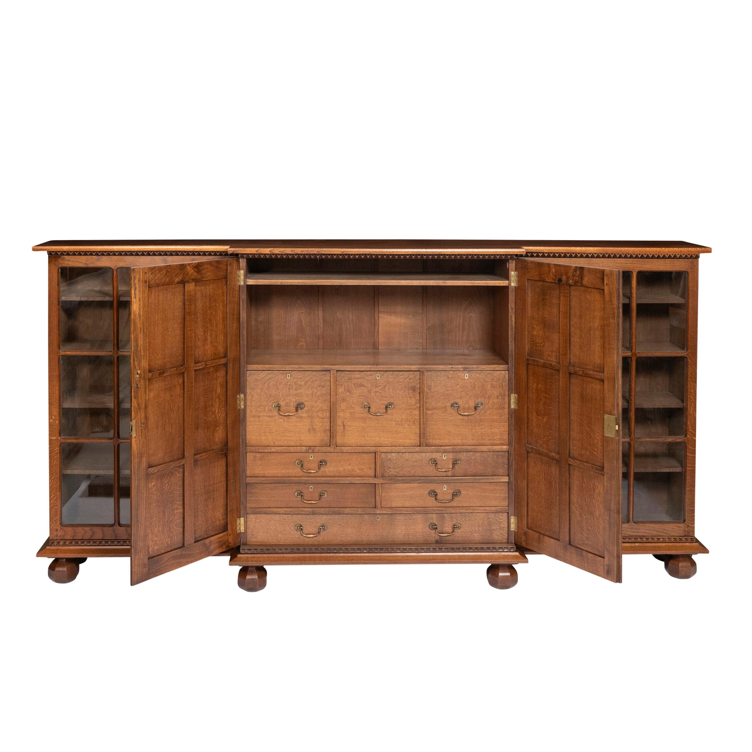 An Arts and Crafts Breakfront low Bookcase Cabinet by Stanley Webb Davies, England circa 1925.
Beautiful craftsmanship
Incised artists mark and craftsman mark inside the central door.
Oak, with original glazed doors.

137 cm high x 254 cm wide x
