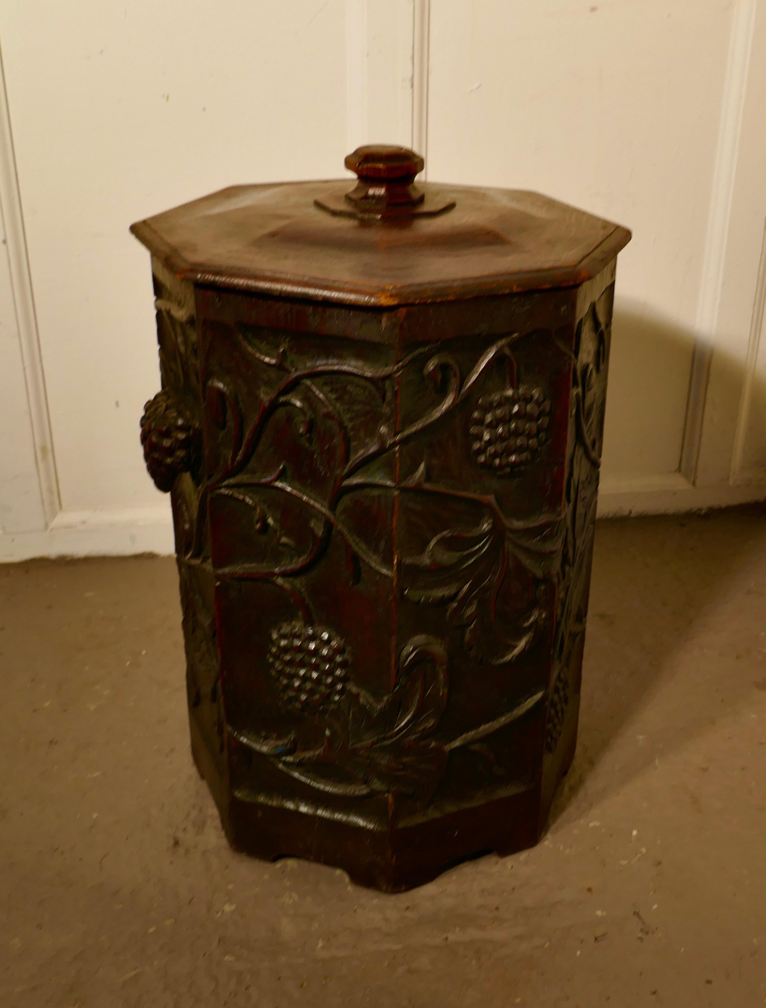 Arts and Crafts Carved Oak Coal or Log Bucket

This is a superbly carved piece, the bin is 8 sided with a lid and a metal lift out liner. (Not marked but expected to be Liberty)
The Bin is beautifully carved with large stylised fruits and  Leaves in