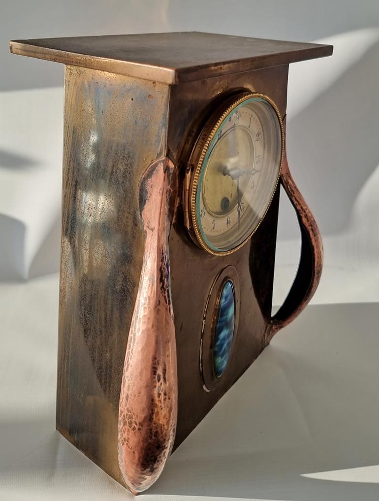 A fine Arts & Crafts copper and brass mantle clock by Beldray of Bilston with inset Ruskin type cabochon, the 8 day pendulum driven movement stamped Rex. The dial with arabic numerals. The underside of the case stamped Beldray for Beldray Ltd.