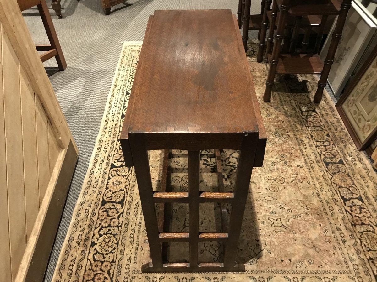 An Arts and Crafts Cotswold School drop leaf dining table with lattice work ends and exposed tenons to the top, the legs united by twin floor stretchers.
Made from London Plane. London Plane is a strong but light weight wood with a dark flecky