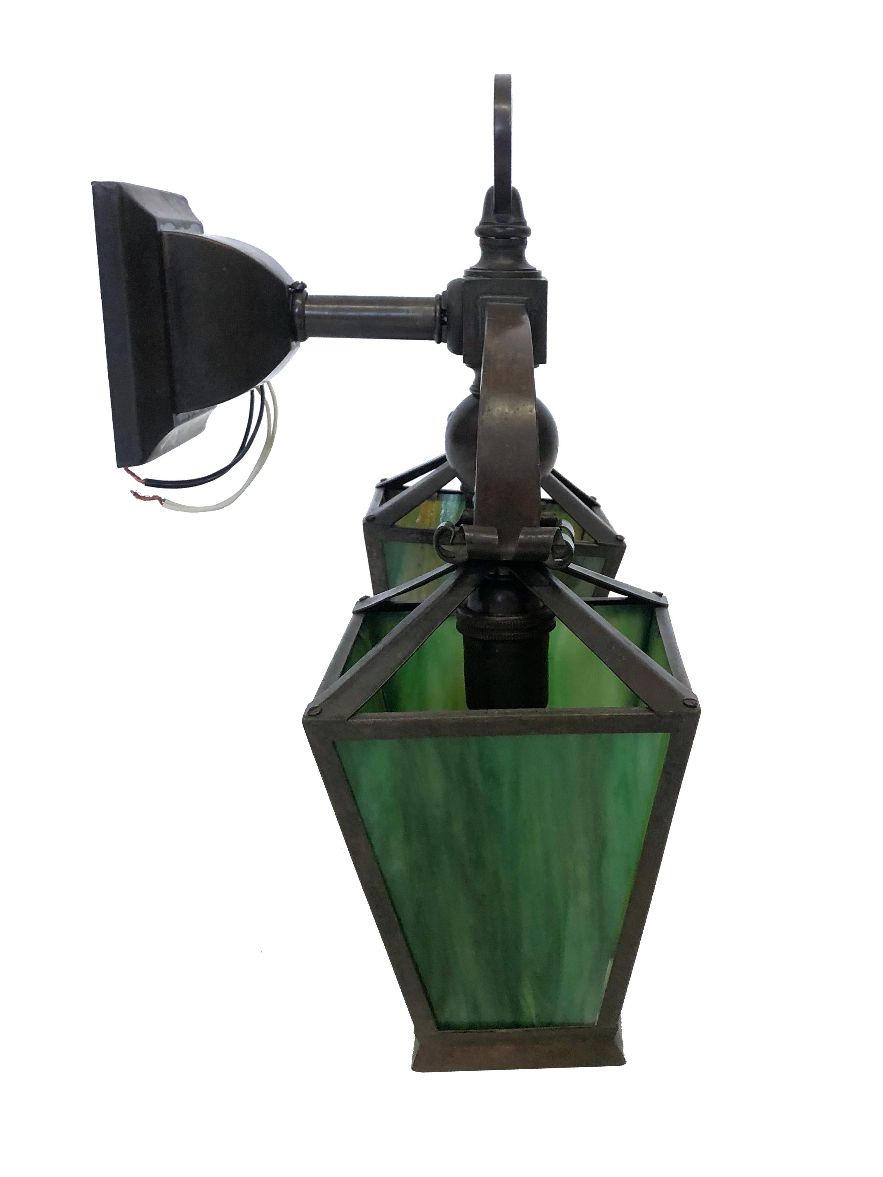 An antique Arts and Crafts double-light sconce, with tapered four-sided green marbled glass lantern shades. The metalwork in this piece is all in age-darkened brass, circa 1920.
Measures: Overall: 15