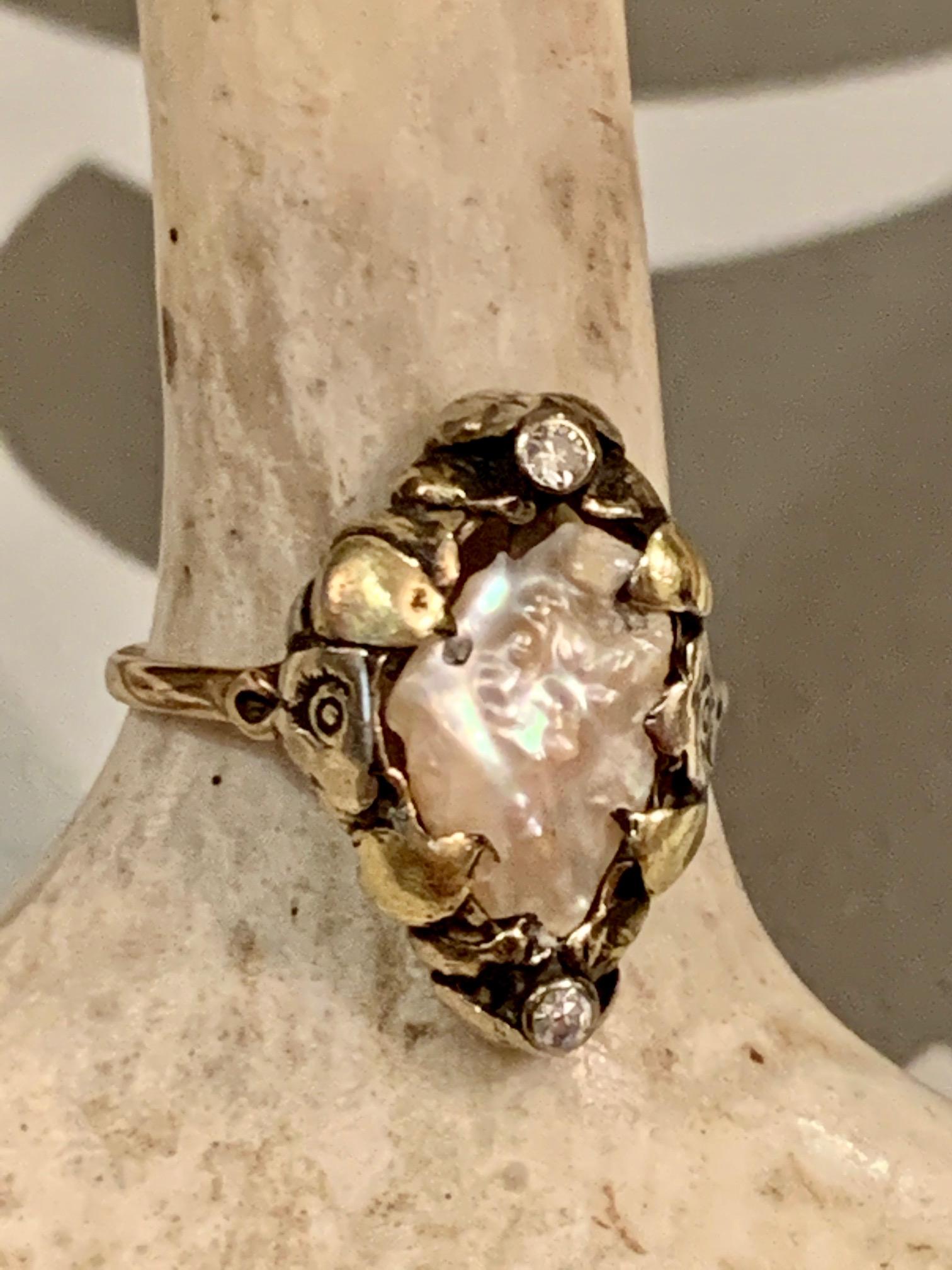 This Arts and Crafts, early 1900's ring features a freshwater Pearl set in 14 karat Yellow Gold.  There are two small Diamonds accenting the ring, with a total weight of .05tcw.

Size:  6 1/4
Weight: 3.4 grams