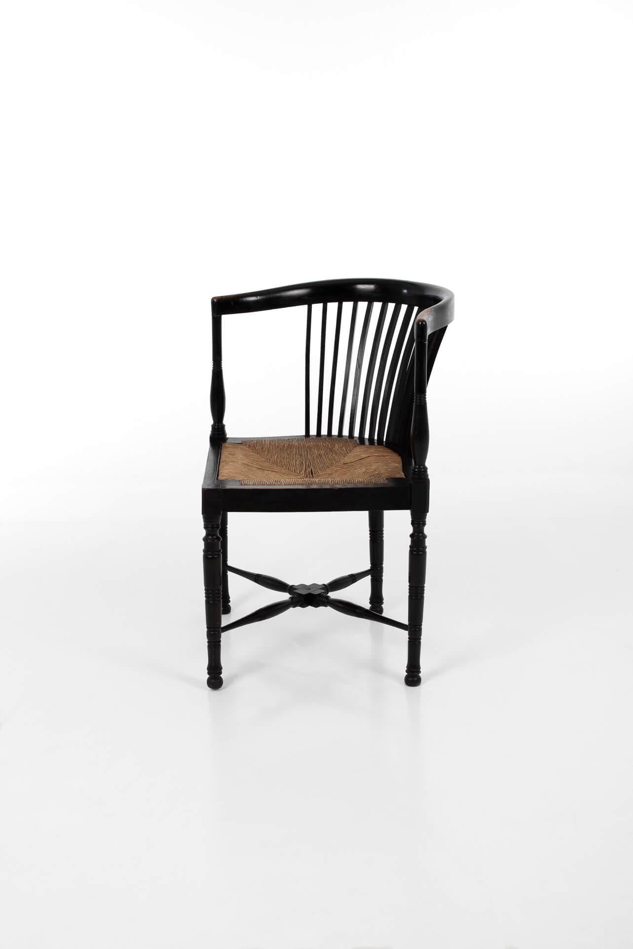 Fabulous ebonised Arts and Crafts corner chair. In original condition with lovely wear to both arms. Complete with the original drop-in woven rush seat. 
British, circa 1900.

Additional Information:
H 71 cm (H 27.9 inches)
W 55 cm (W 21.6