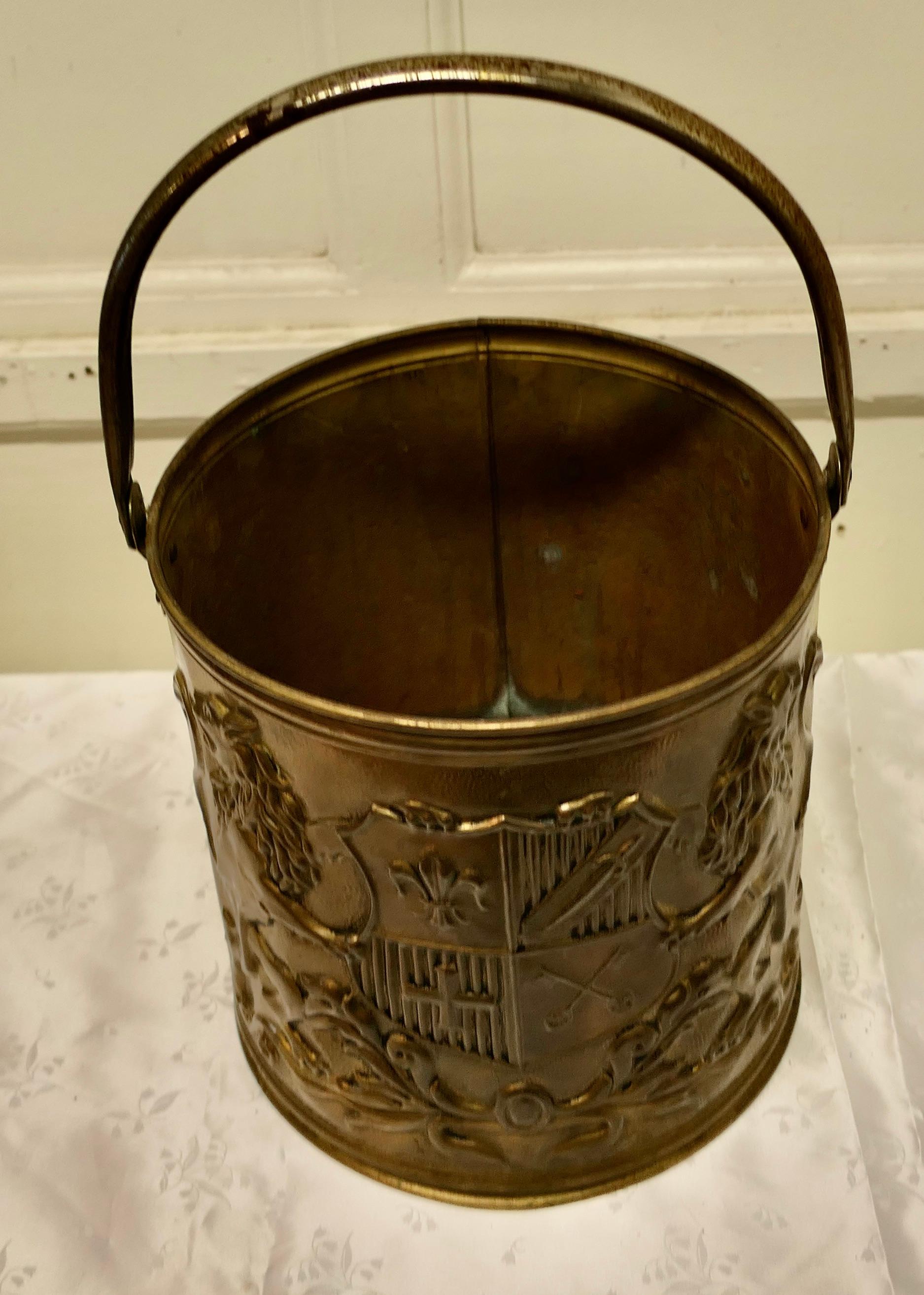 Arts and Crafts Embossed brass coal bucket

This good looking piece it is round in shape with a Royal Crest embossed on the front. The heraldic crest is supported by a Rampant Lion on each side, it has hooped carrying handle and would grass any