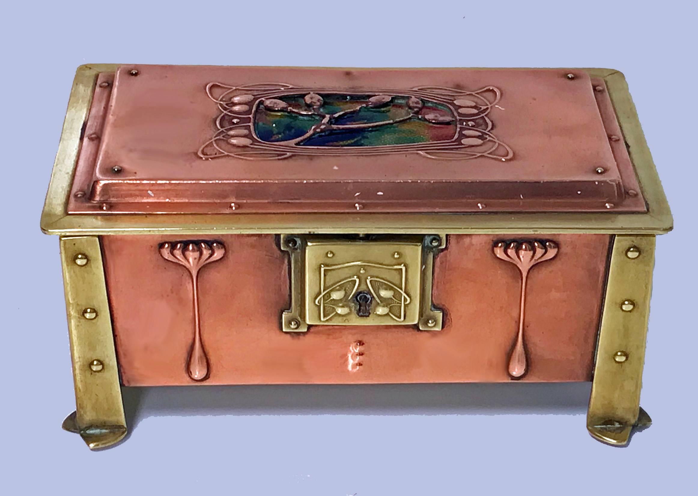 Arts & Crafts enamel, copper and brass box, circa 1900. The box of four turned rivet bracket brass cornices, the panelled copper body with stylised arts and crafts decoration, the cover with blue, green, yellow and red design enamel background to