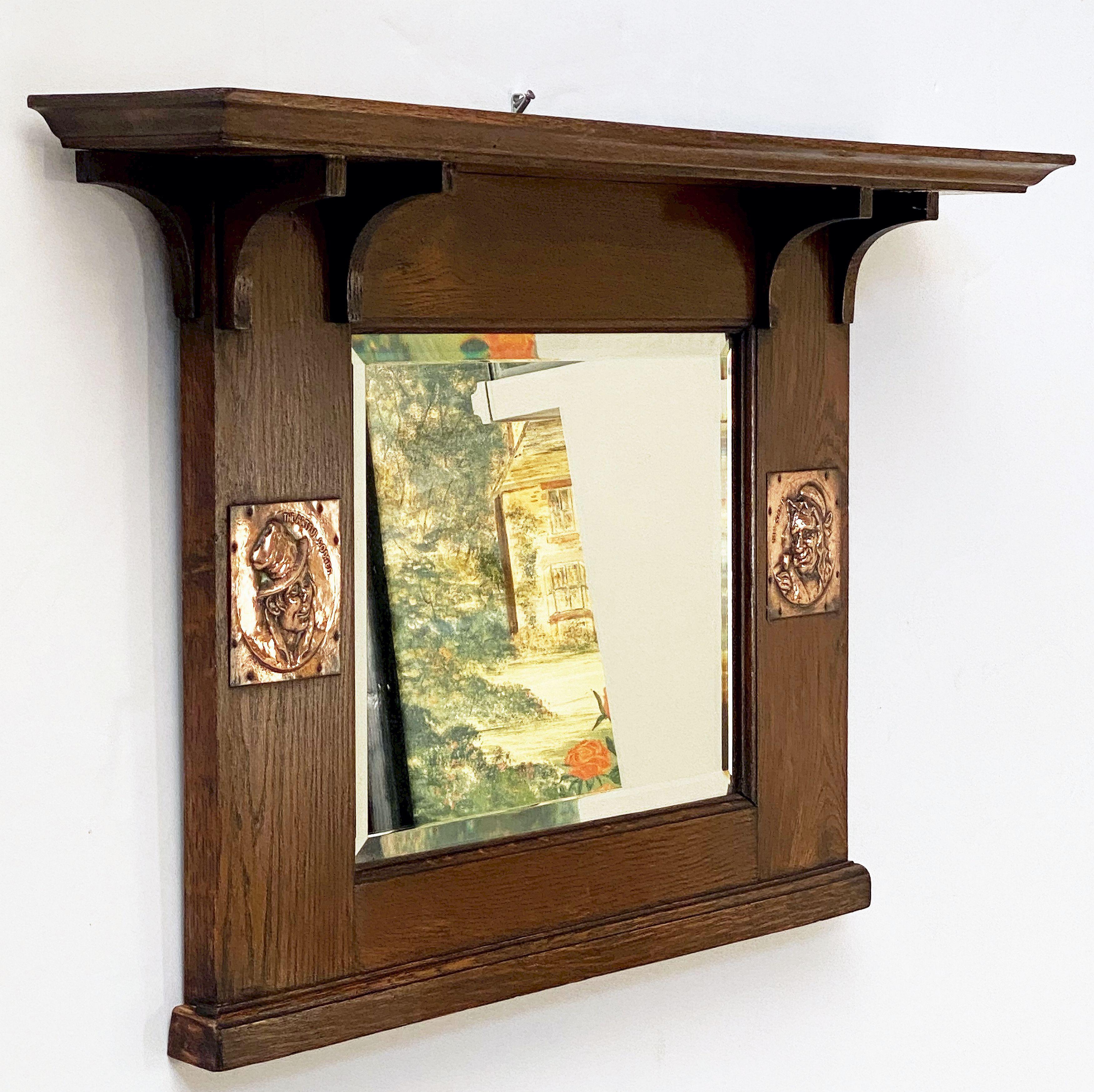 A fine English rectangular overmantle wall mirror of oak from the Arts and Crafts Era, featuring a crown moulding top over a beveled glass mirror with opposing decorative relief cartouches depicting The Artful Dodger and Mrs. Gamp - spurious
