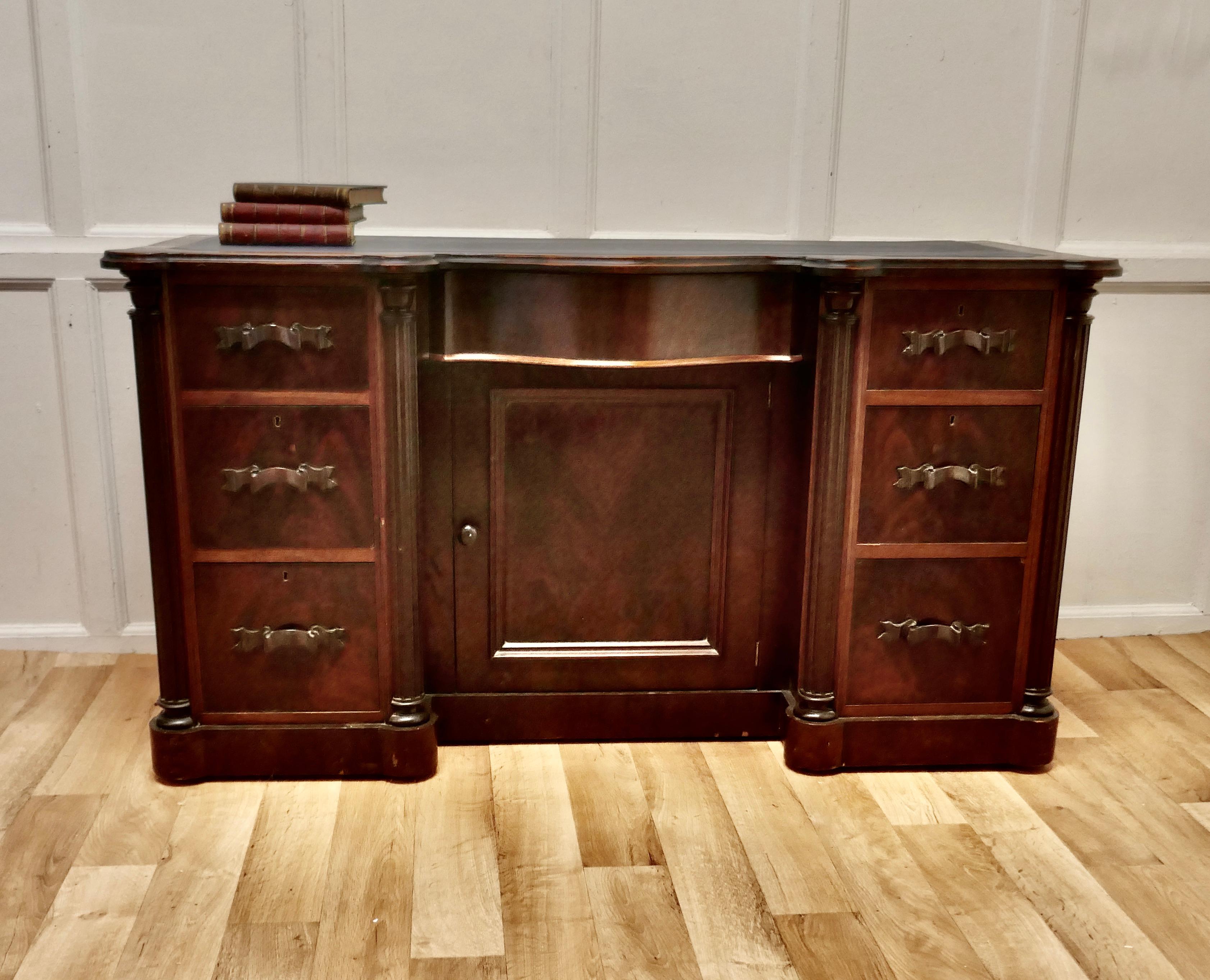 Arts & Crafts flame mahogany knee hole writing desk.

This superb desk is in one piece it has twin pedestals with a shelved cupboard and a concealed bow front drawer in the centre, the top is a twin pedestal serpentine shape and the leather is