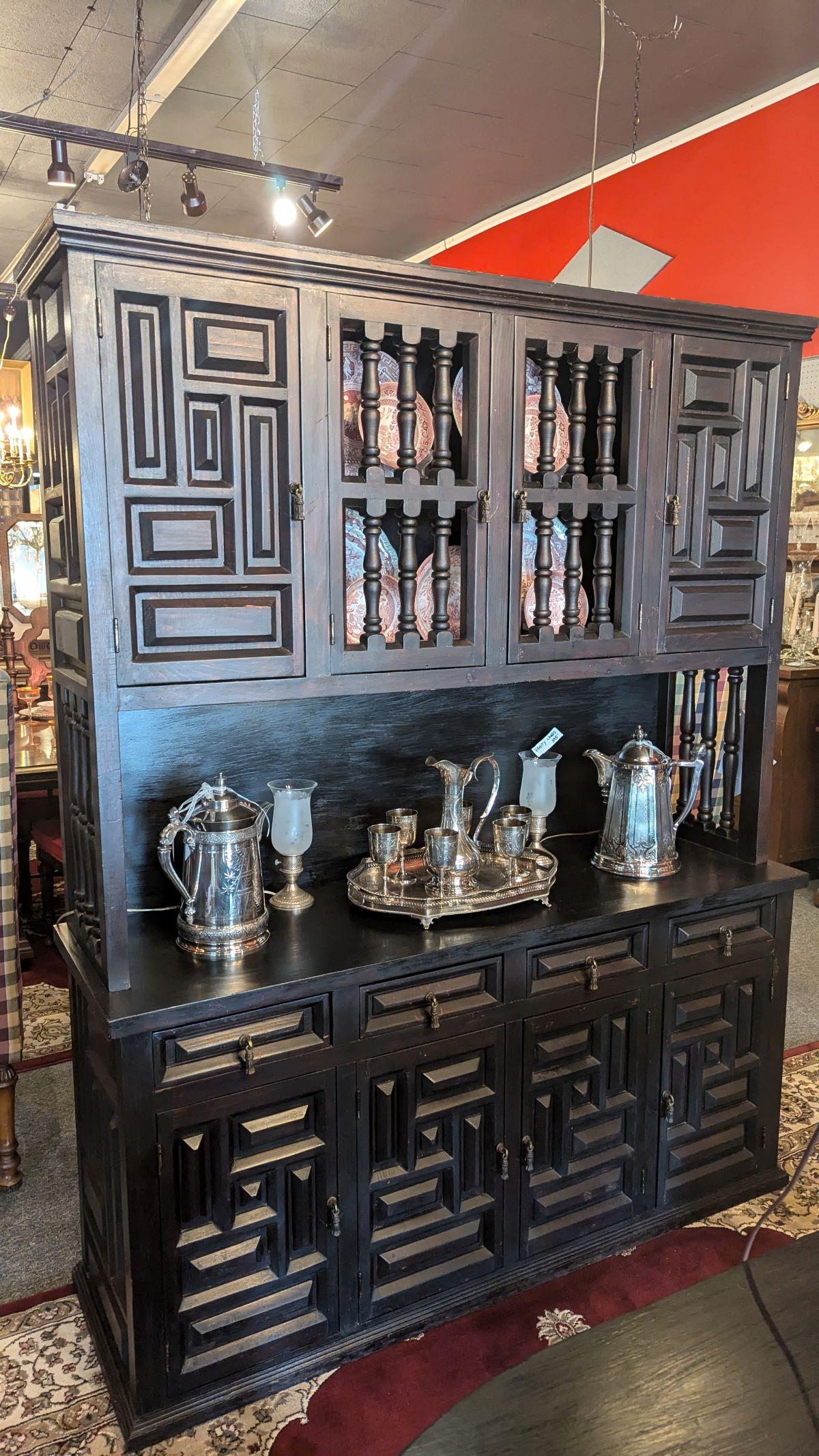 This is a fabulous Arts and Crafts Flemish ebonized sideboard cabinet with geometric accents throughout. Flush base, four lower doors topped by four drawers, open galley with turned side supports, topped by two paneled doors and two turned doors. 