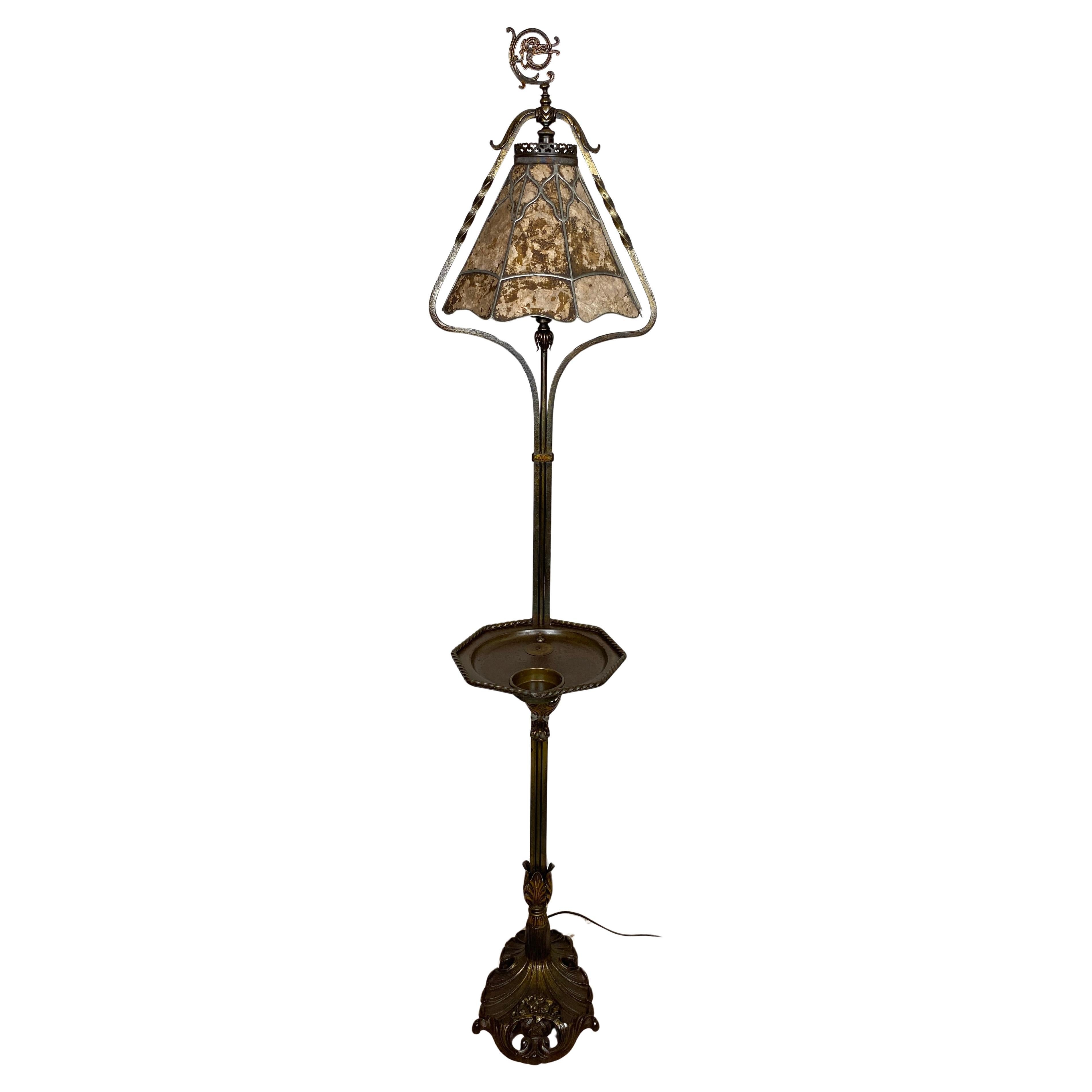 American Arts and Crafts Style Floor Lamp with Original Mica Shade and Table Top

Crest and Co. iron floor lamp with brass accents and an original leaded mica shade. It features a center tabletop with original, brass insert. It is a great size to